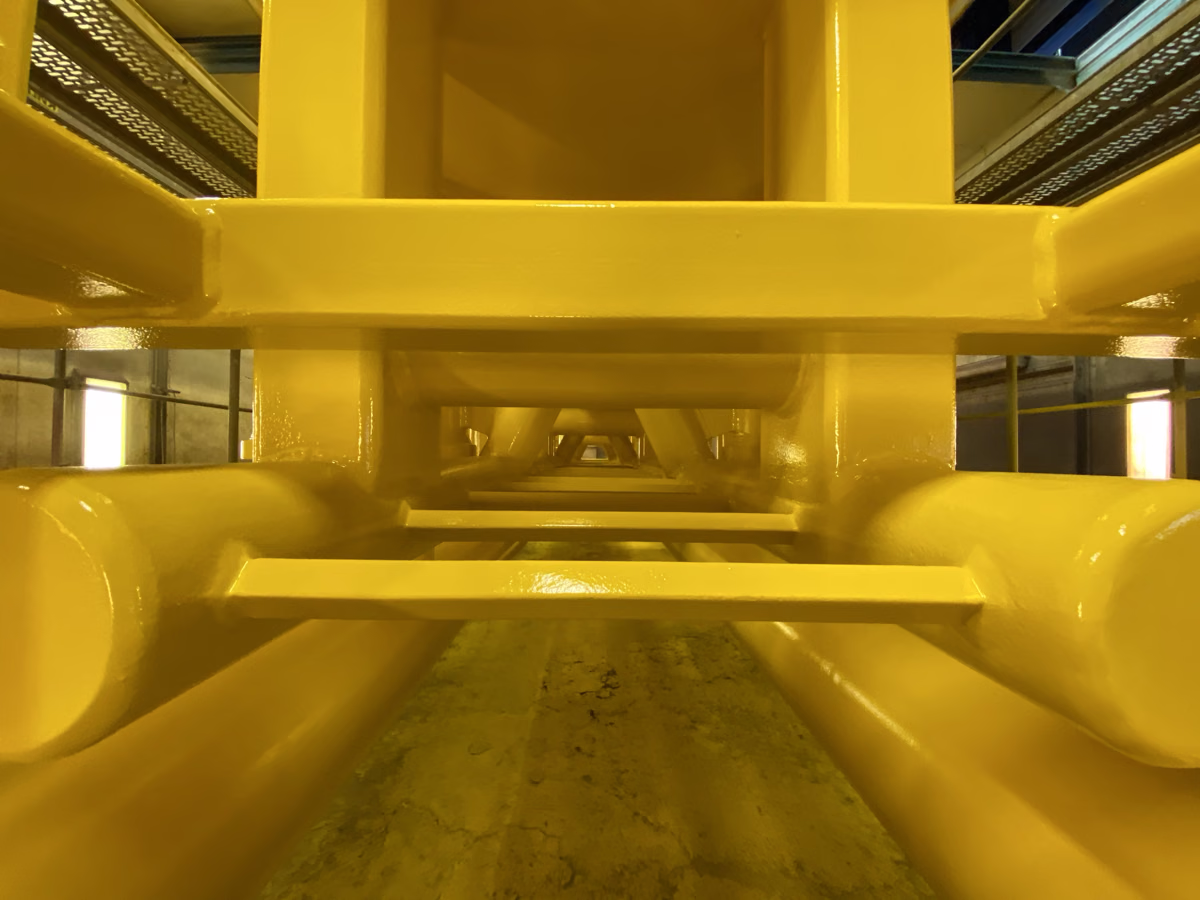 Monteur am gelben Transition Piece einer Offshore-Anlage