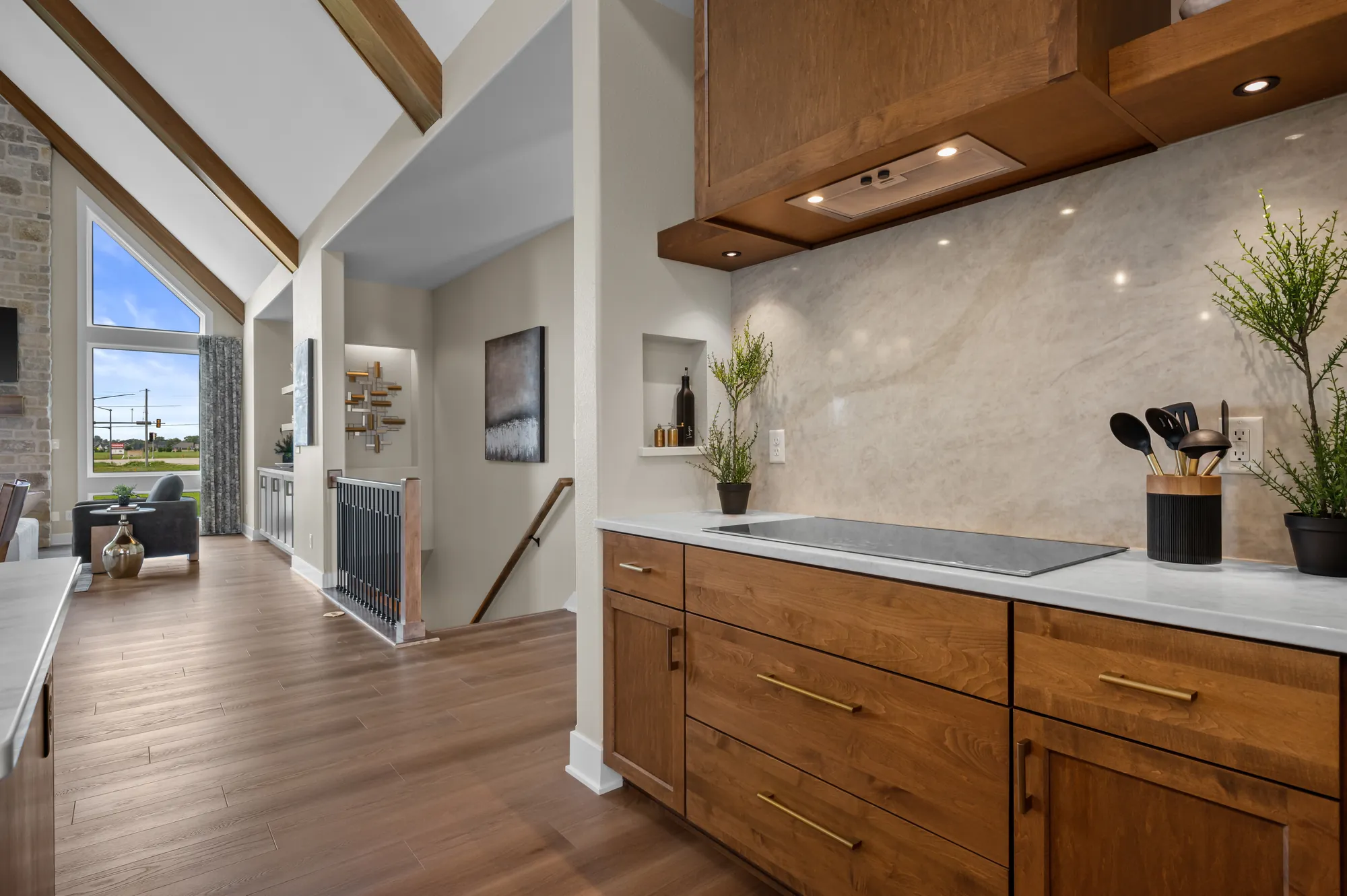Stained wood kitchen cabinetry and hood under a vaulted, beamed ceiling