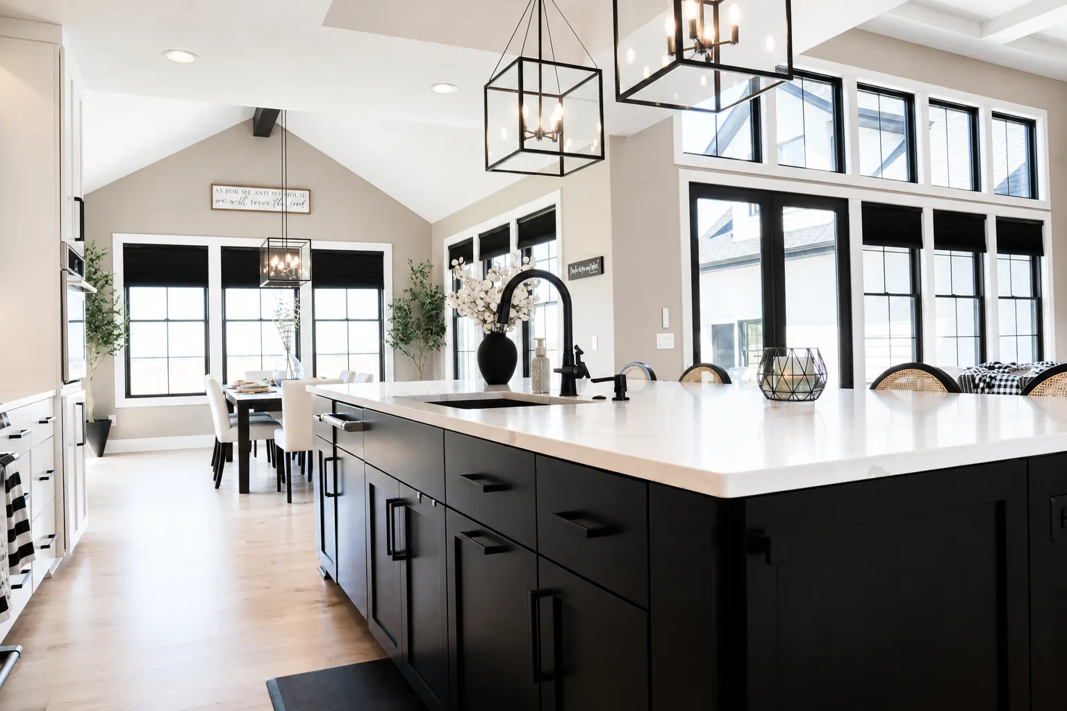 White kitchen with a black island and white quartz countertop under a vaulted ceiling
