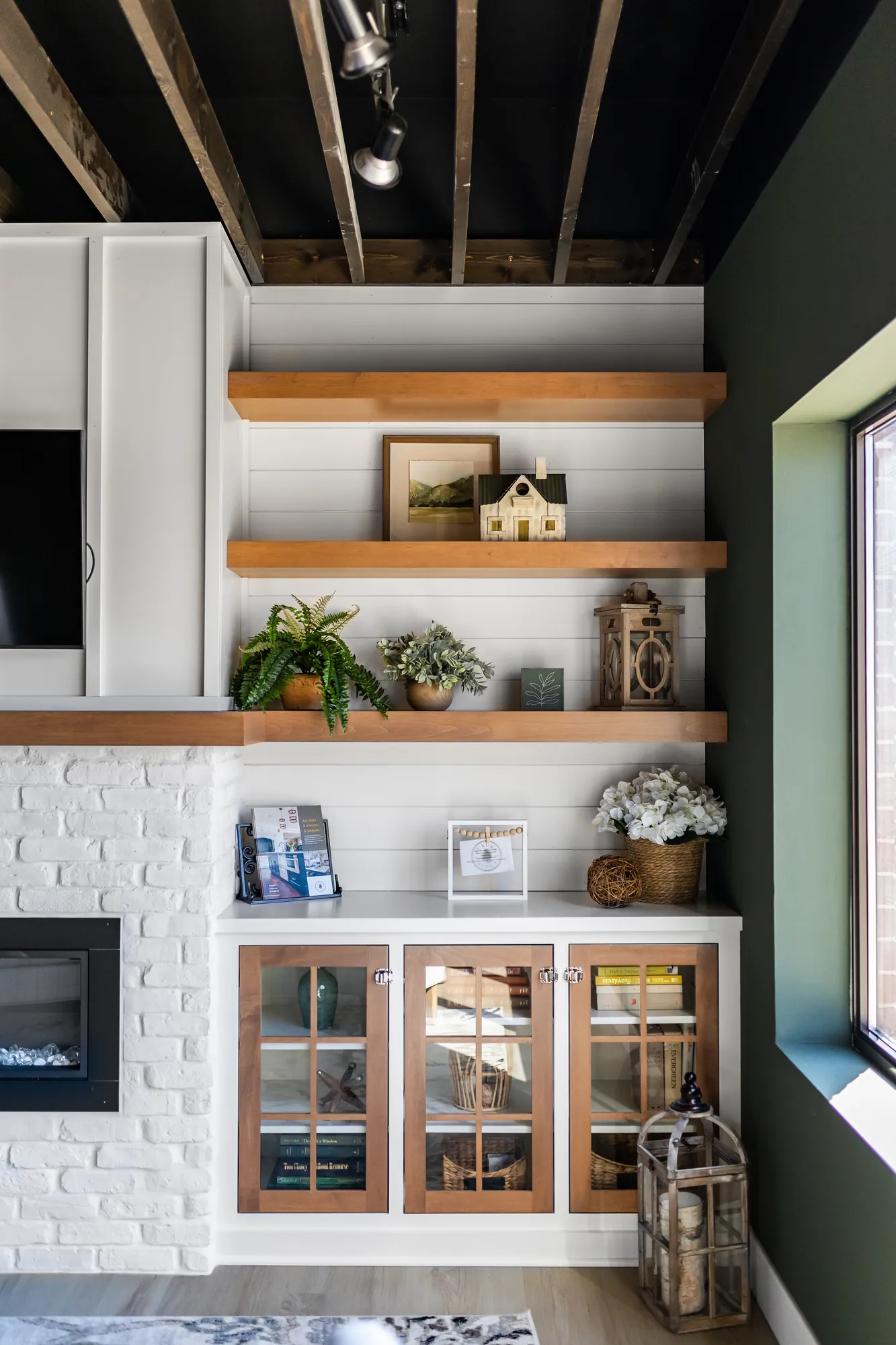 Built-in shelving and glass-front cabinets under exposed ceiling beams