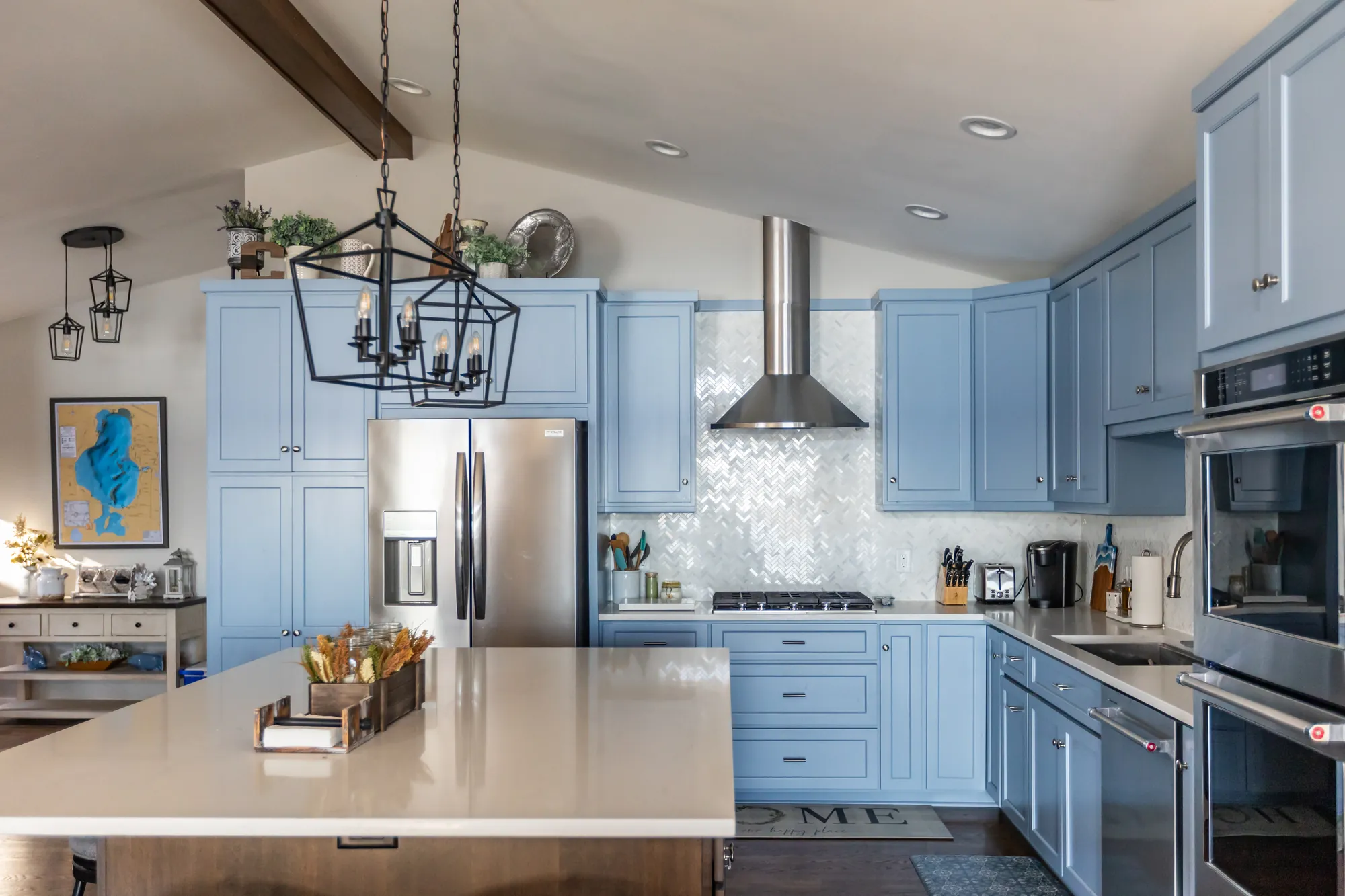 Blue painted kitchen with a quartz island and stainless range hood
