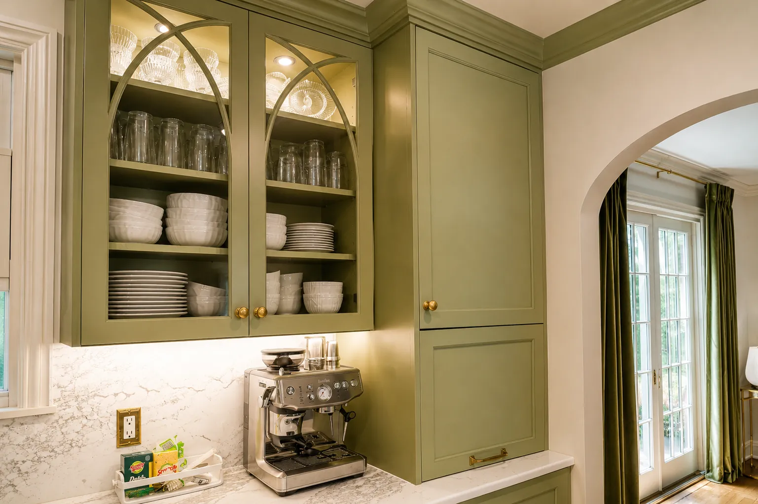 Sage green coffee hutch with arched glass-front upper cabinets