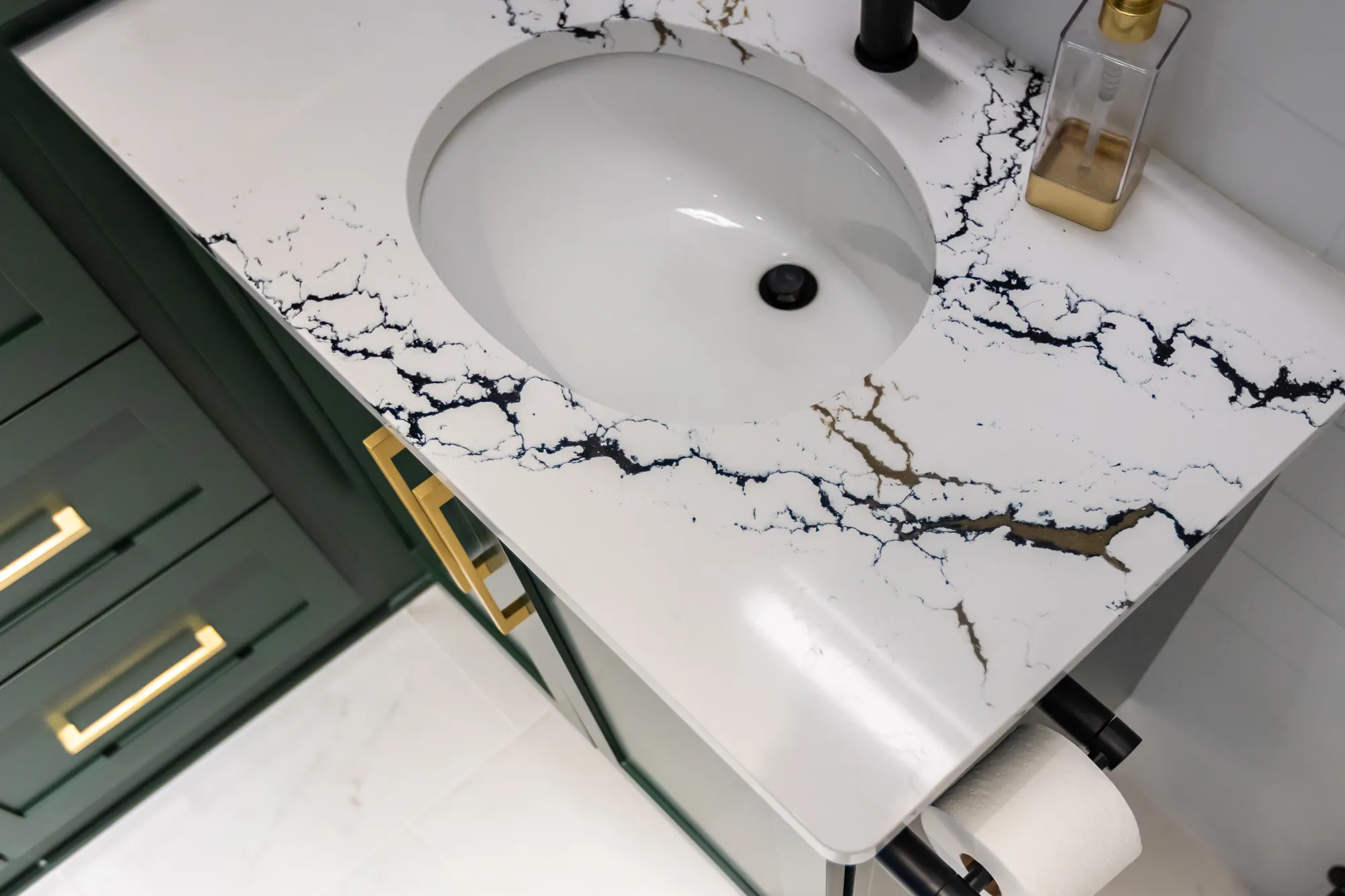 Veined quartz vanity top with an undermount sink over green cabinetry