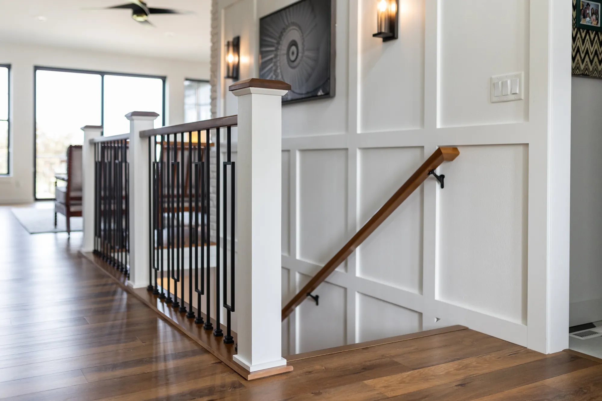 Staircase with iron balusters, a wood handrail and board-and-batten wainscoting
