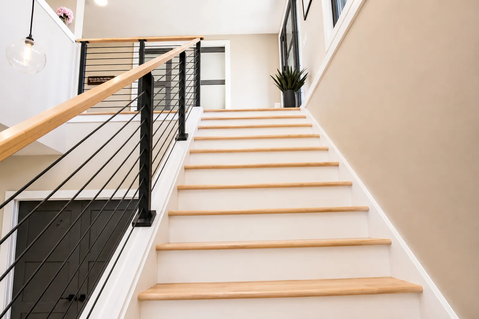 Staircase with a wood handrail, cable railing and wood treads