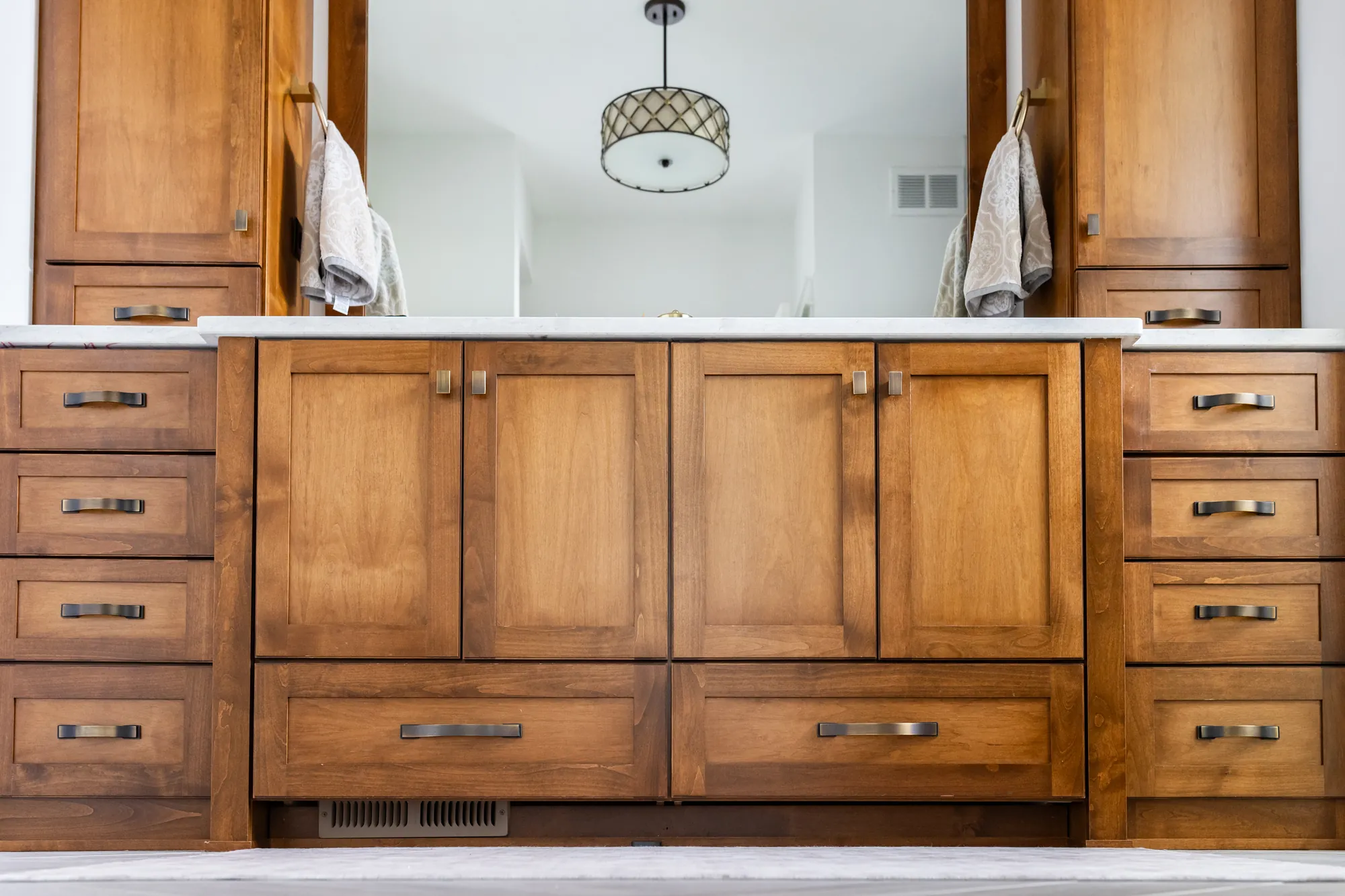 Stained wood double vanity with drawer banks and a quartz top