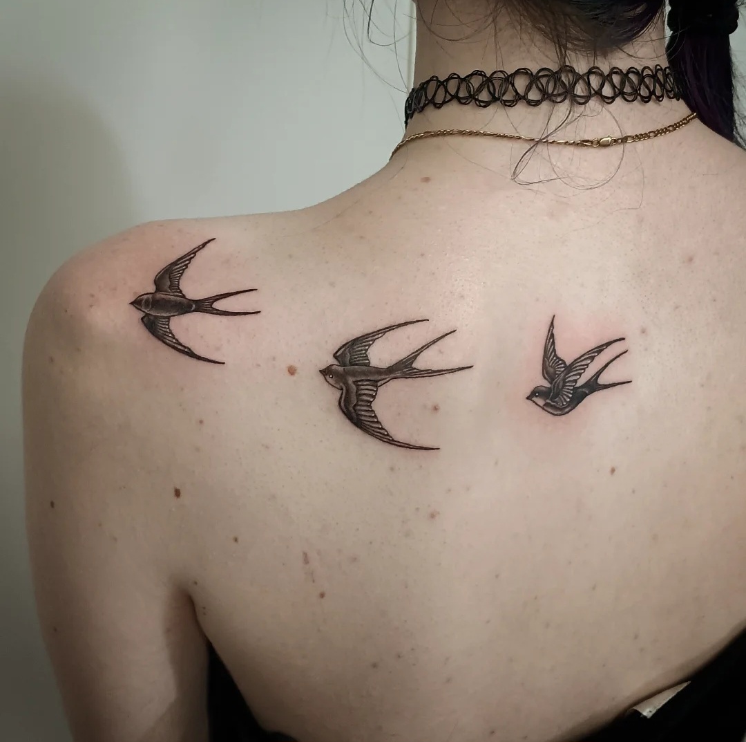 Three swallow tattoos across the upper back by Ramona at Lady Ink