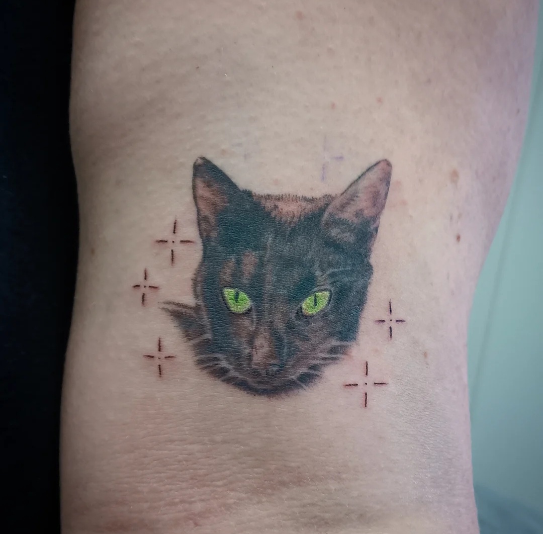 Black cat tattoo with green eyes by Ramona at Lady Ink
