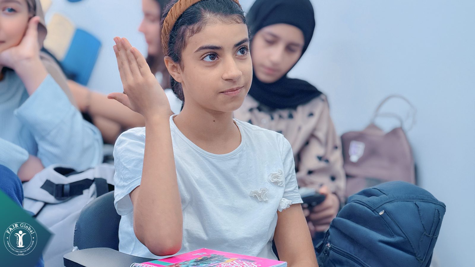 A Palestinian girl raising her hand to answer in class
