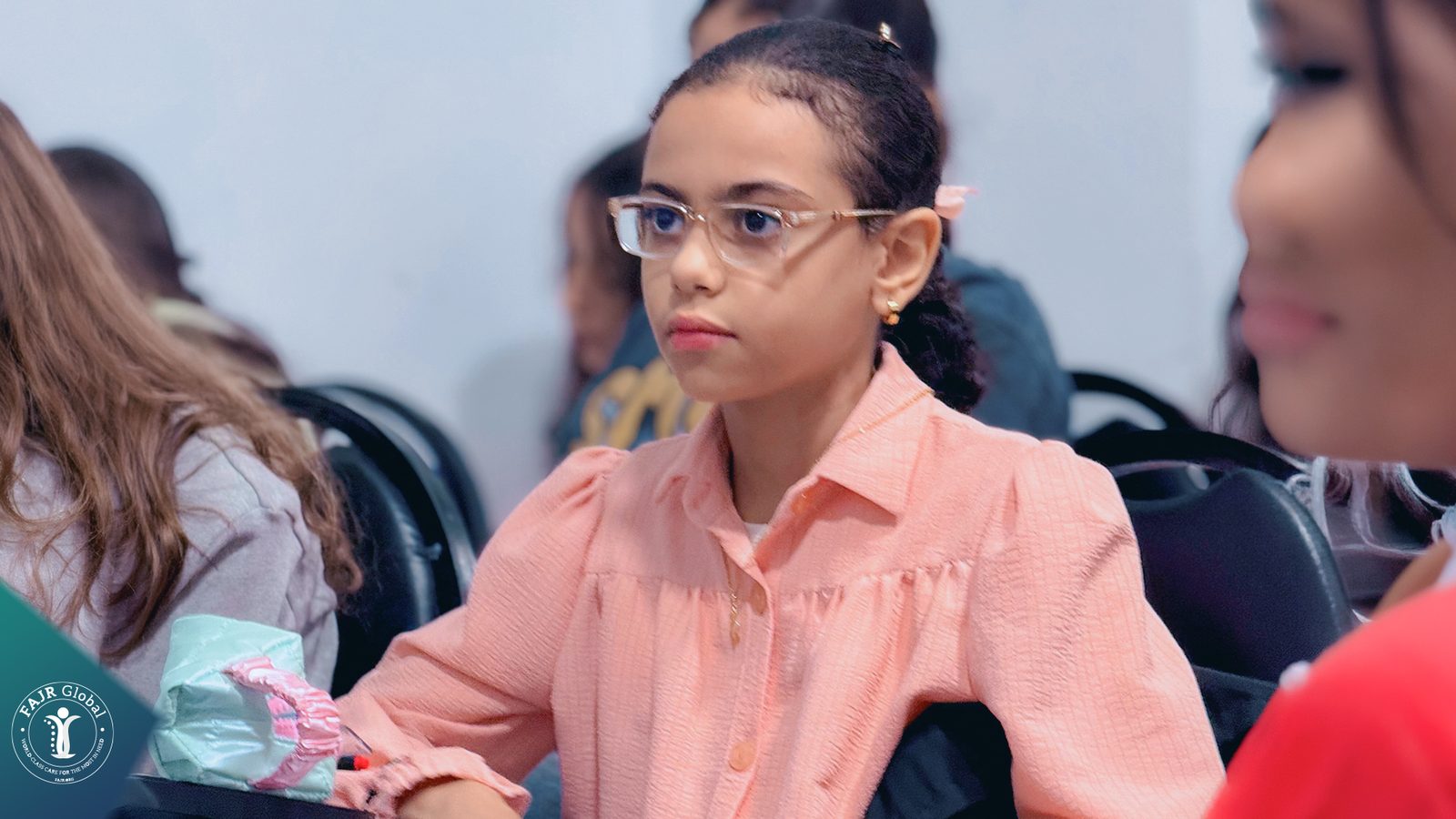 A Palestinian girl in glasses at her desk