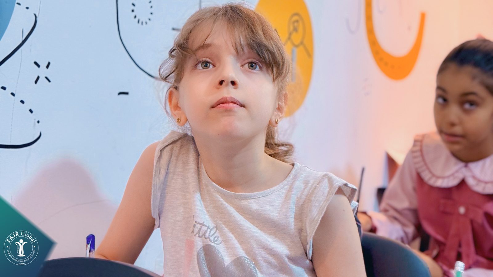 A young girl looking up at the board in class