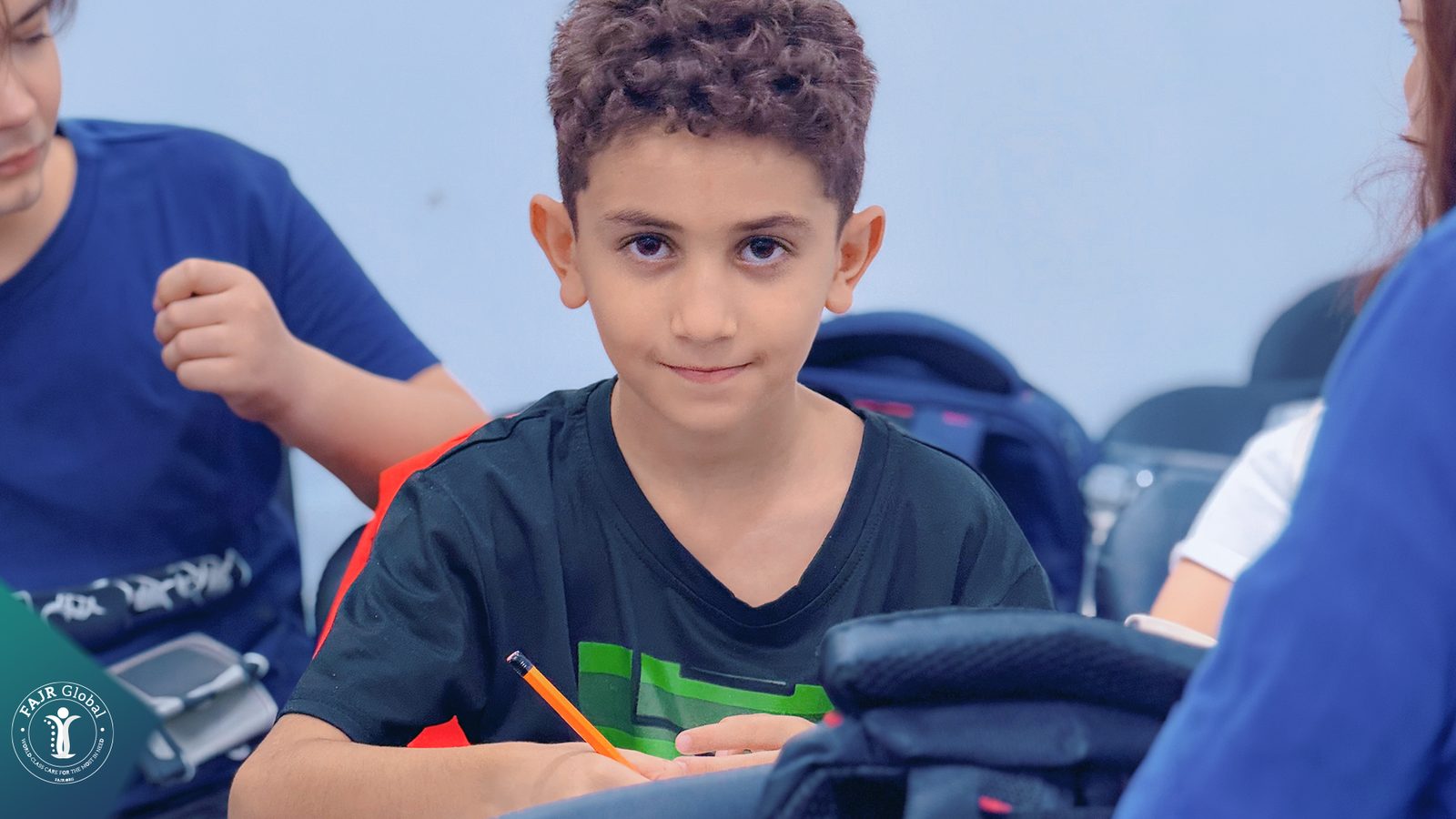 A Palestinian boy smiling at his desk