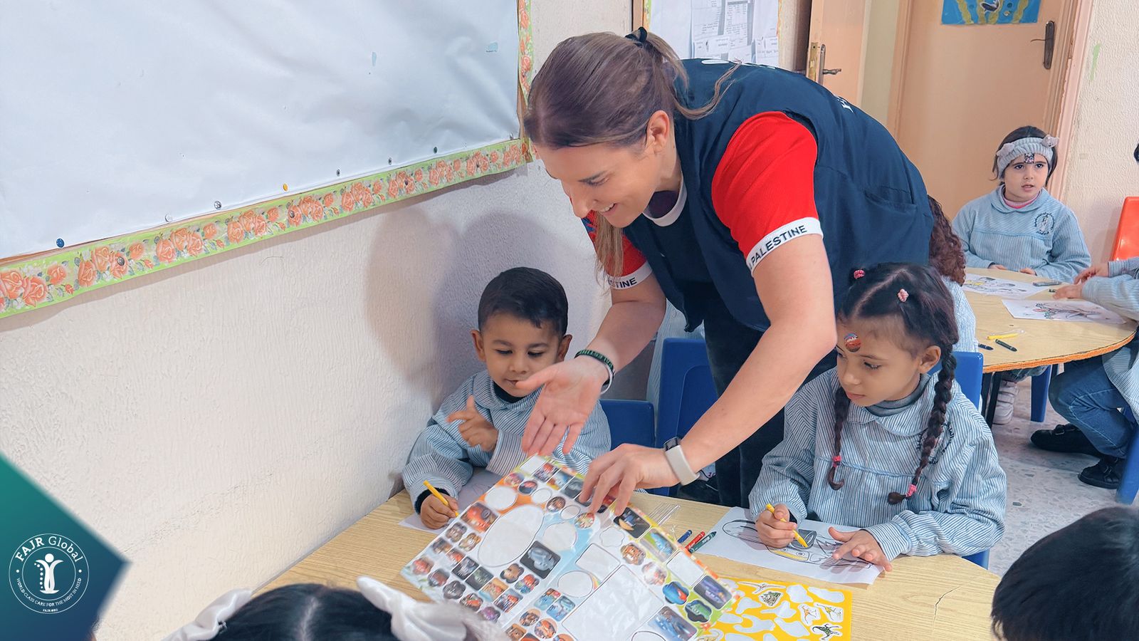 A FAJR Global volunteer helping children with stickers and drawings