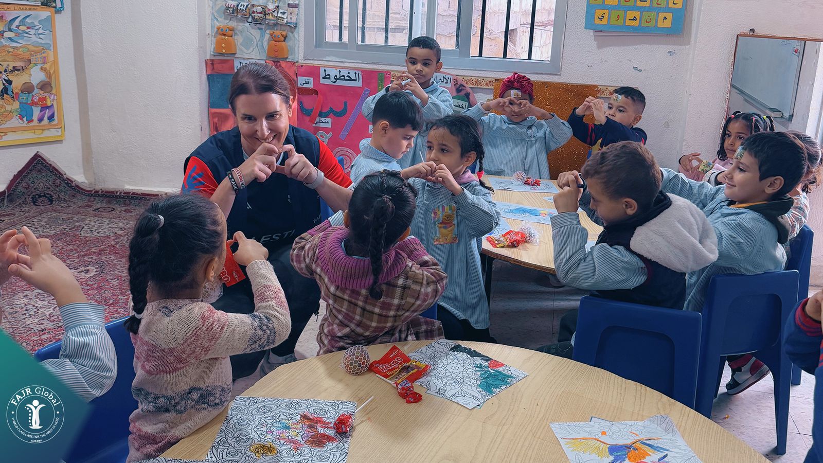 A FAJR Global volunteer playing a game with children around a table
