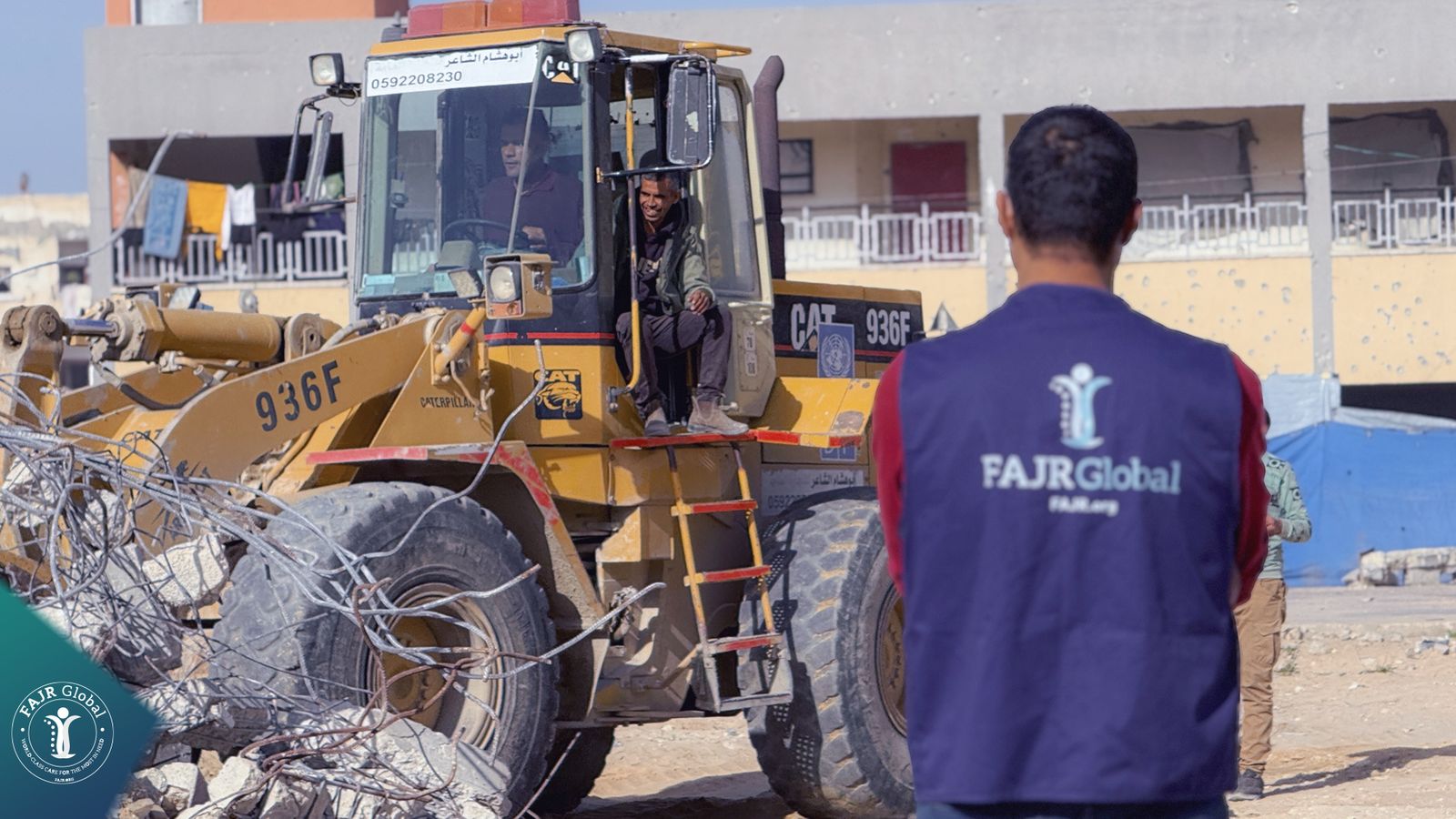 A FAJR Global team member watching a loader clear rubble for a school site