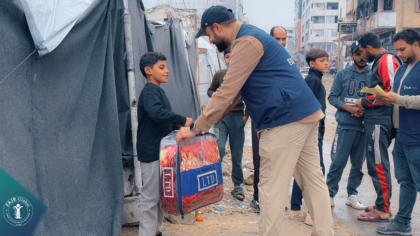 A FAJR Global volunteer delivers a winter blanket bag to a boy