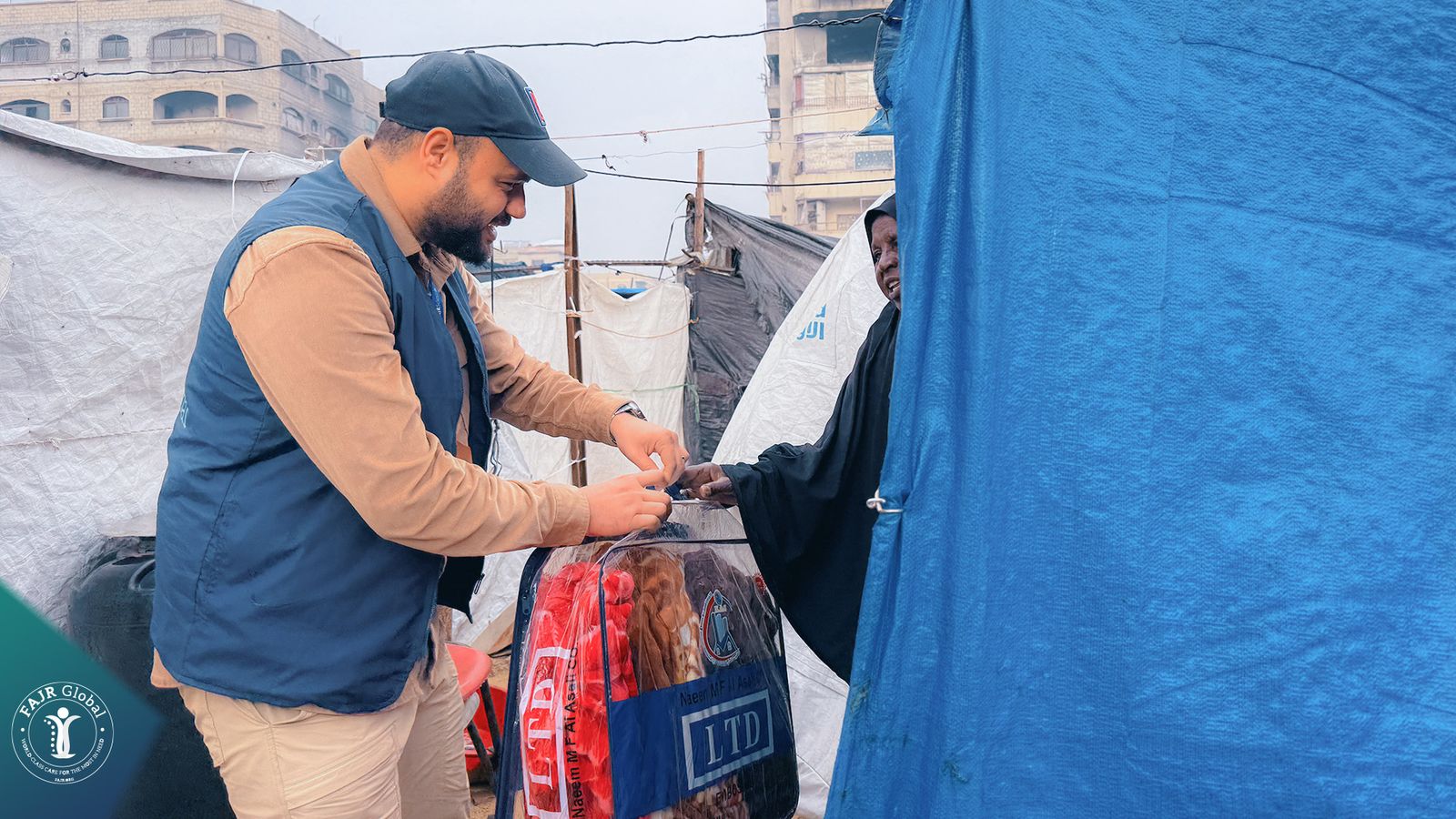 A FAJR Global volunteer delivering a winter blanket bag to a family's tent