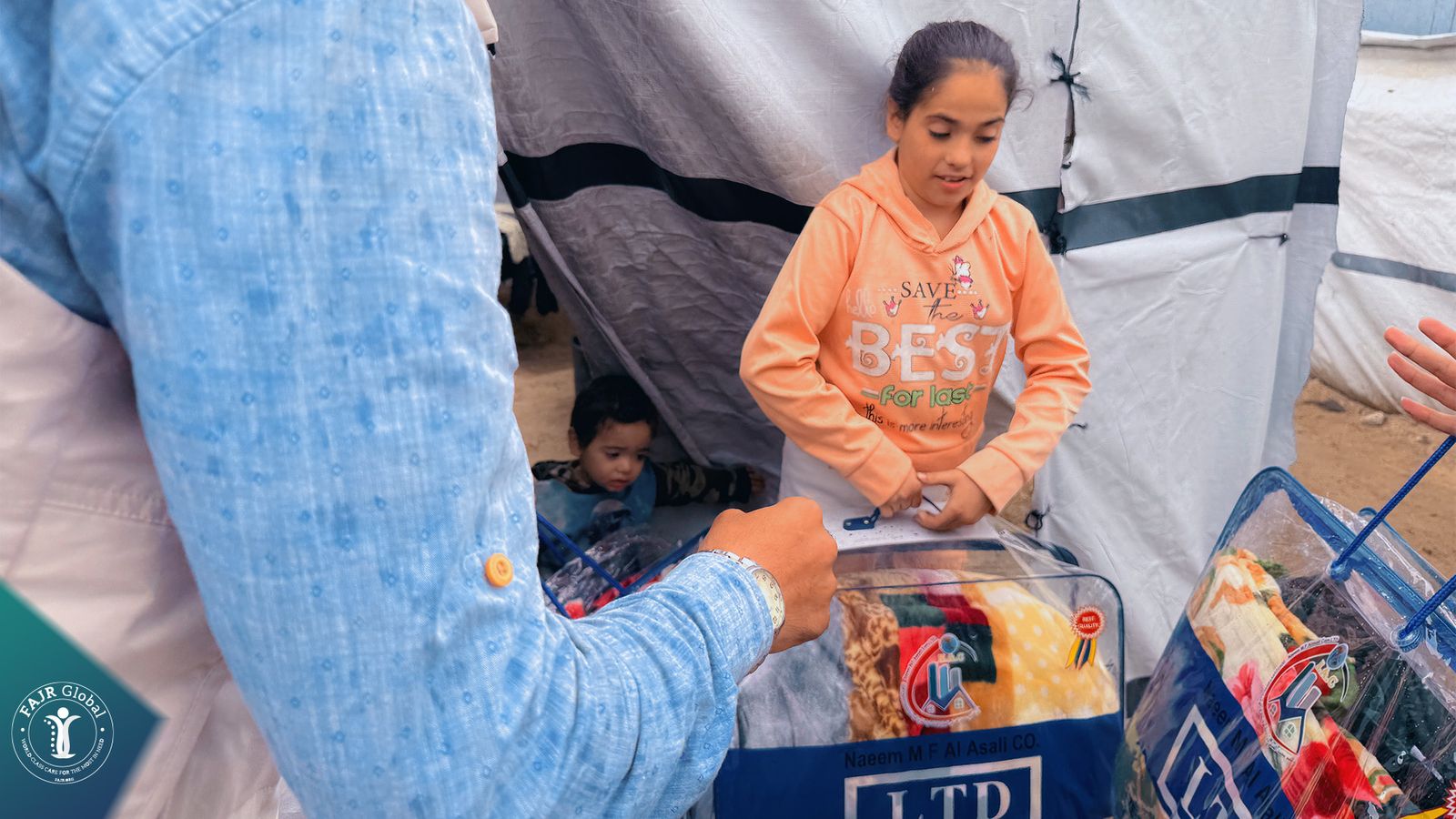 A girl receives a winter blanket bag at her family's tent