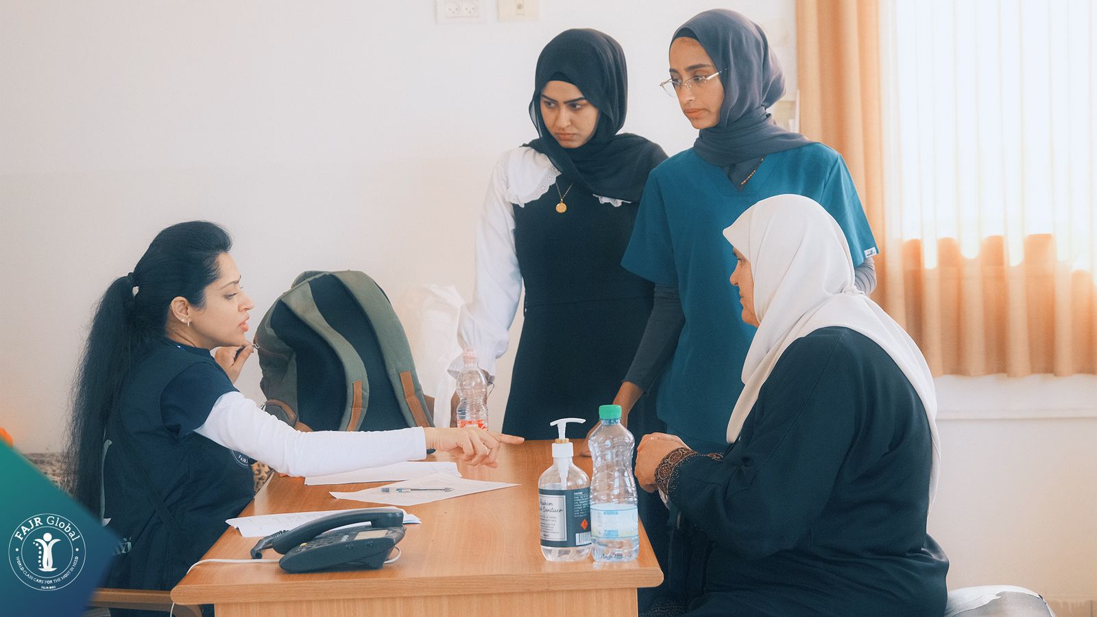 FAJR Global clinicians speaking with visitors at a clinic desk