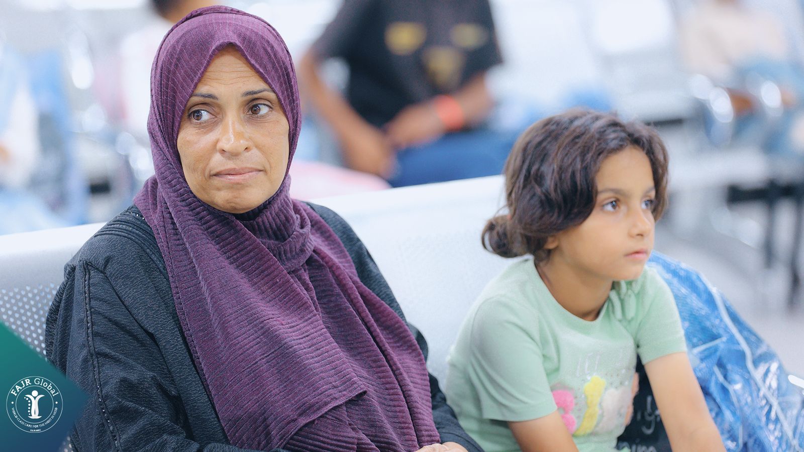 A woman and a young girl sitting together in a hospital waiting area