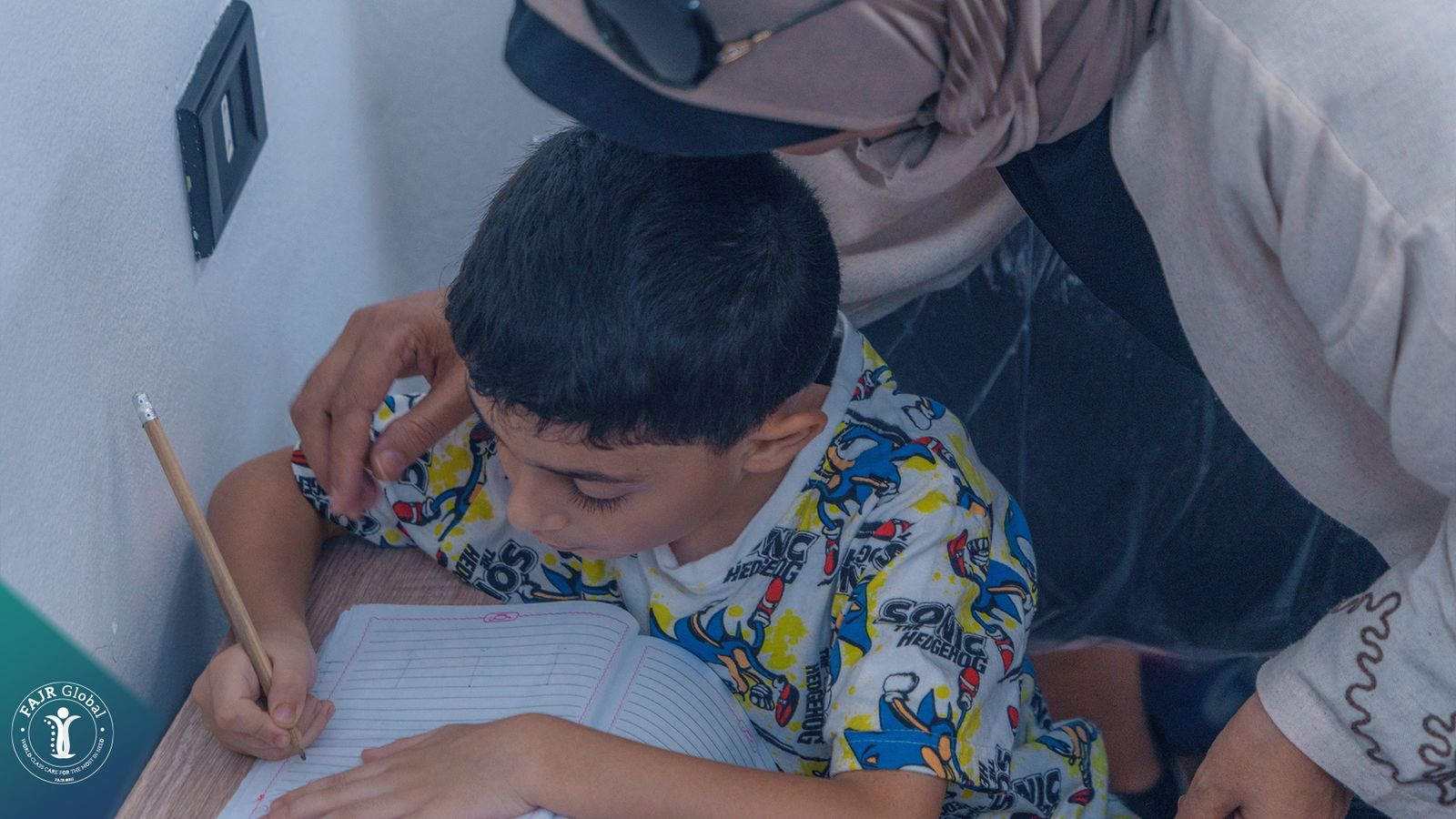 A boy writing in a notebook during a lesson