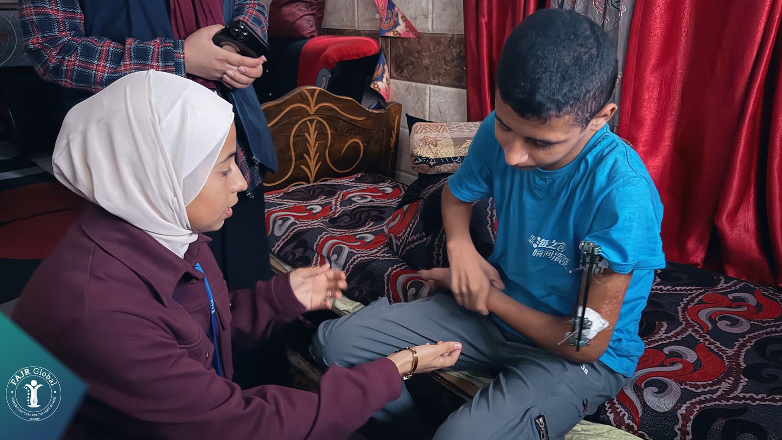 A FAJR health worker examining a young man's injured leg at home