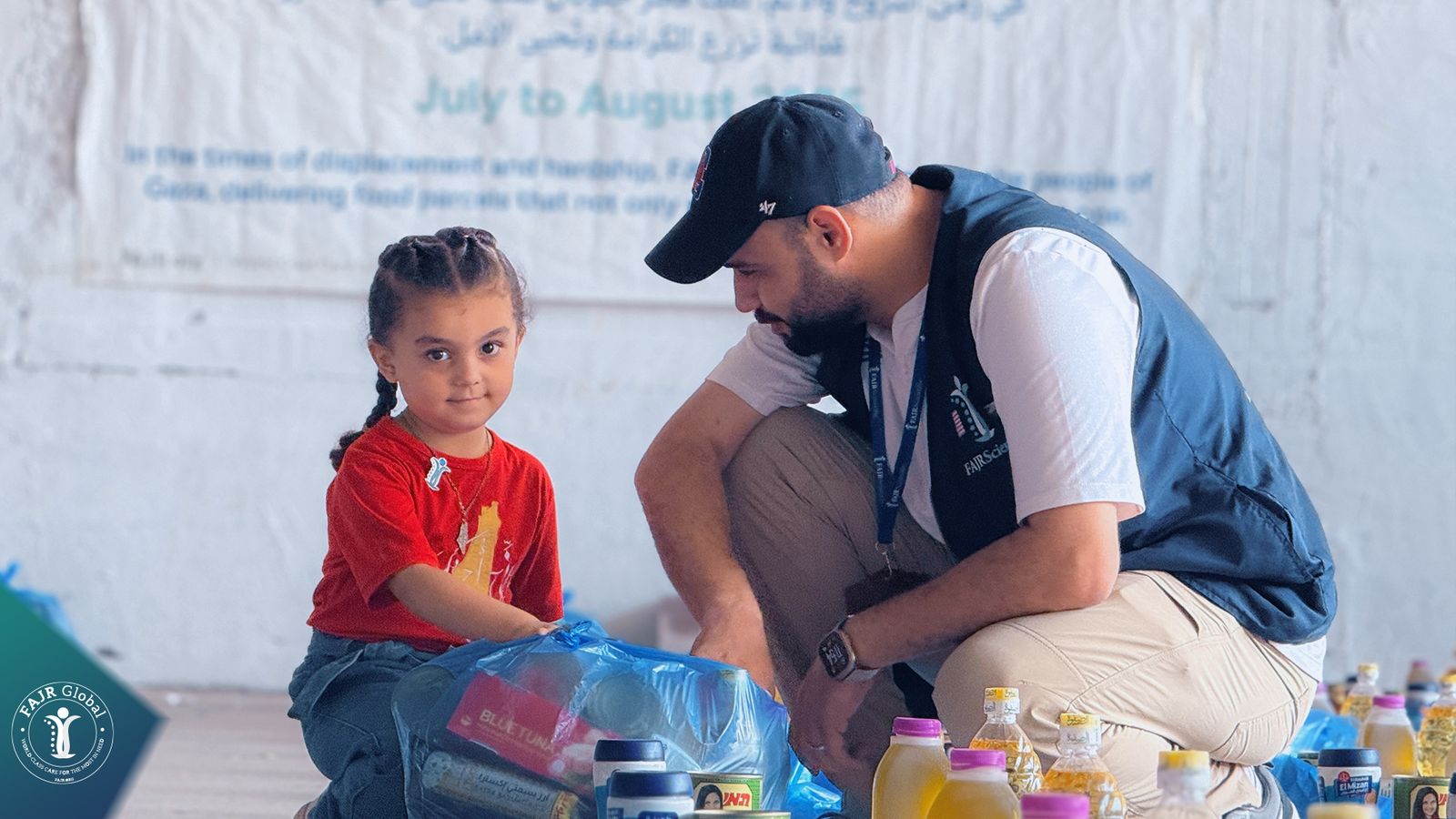 A FAJR relief worker kneeling beside a young girl with a relief package