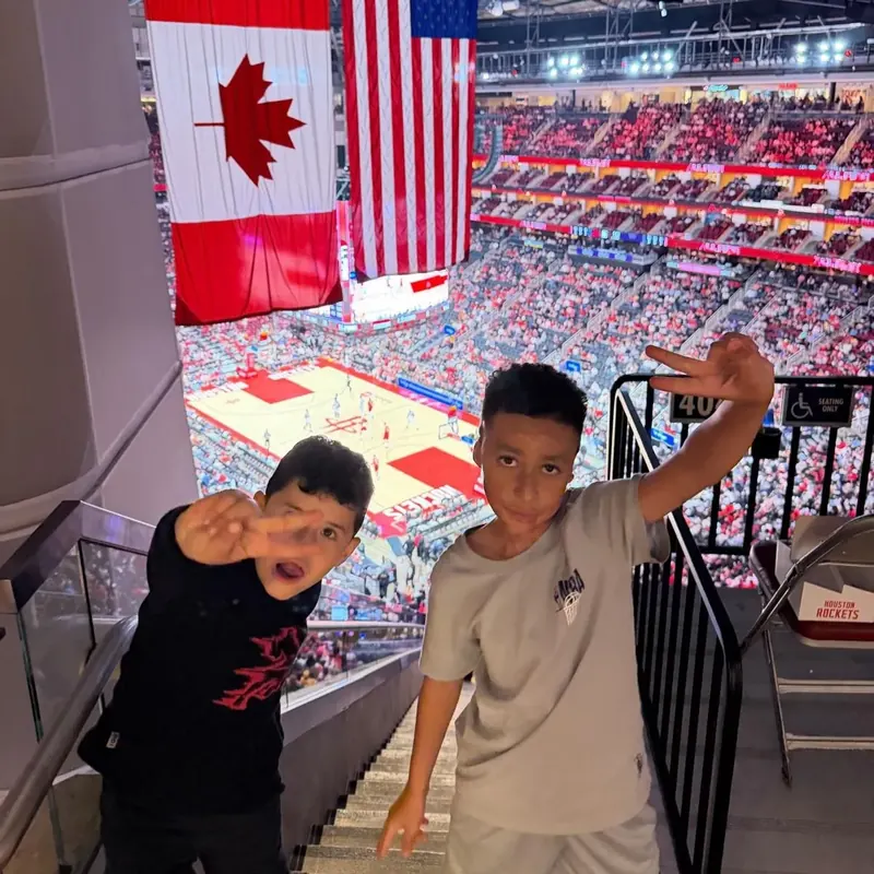 Two boys waving from the stands at the Toyota Center in Houston