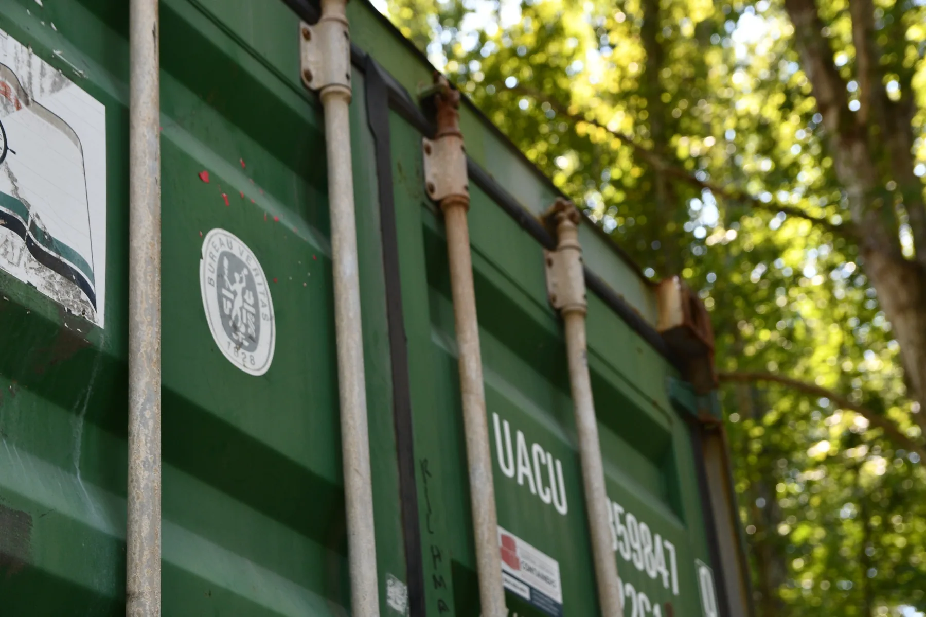 Container being set down from a tilt-deck trailer onto prepared ground