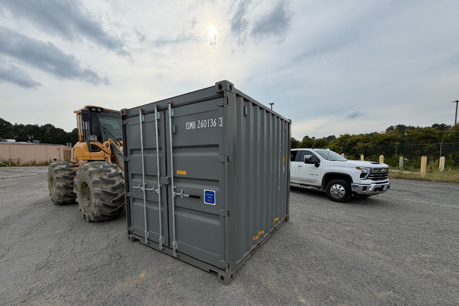 A 10 ft shipping container in the Central Virginia Containers yard, with a pickup truck and wheel loader beside it for scale.