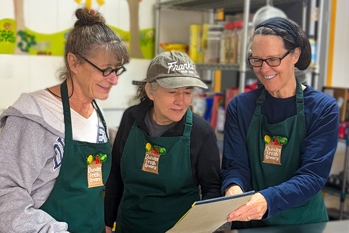 Three smiling volunteers looking at a notebook