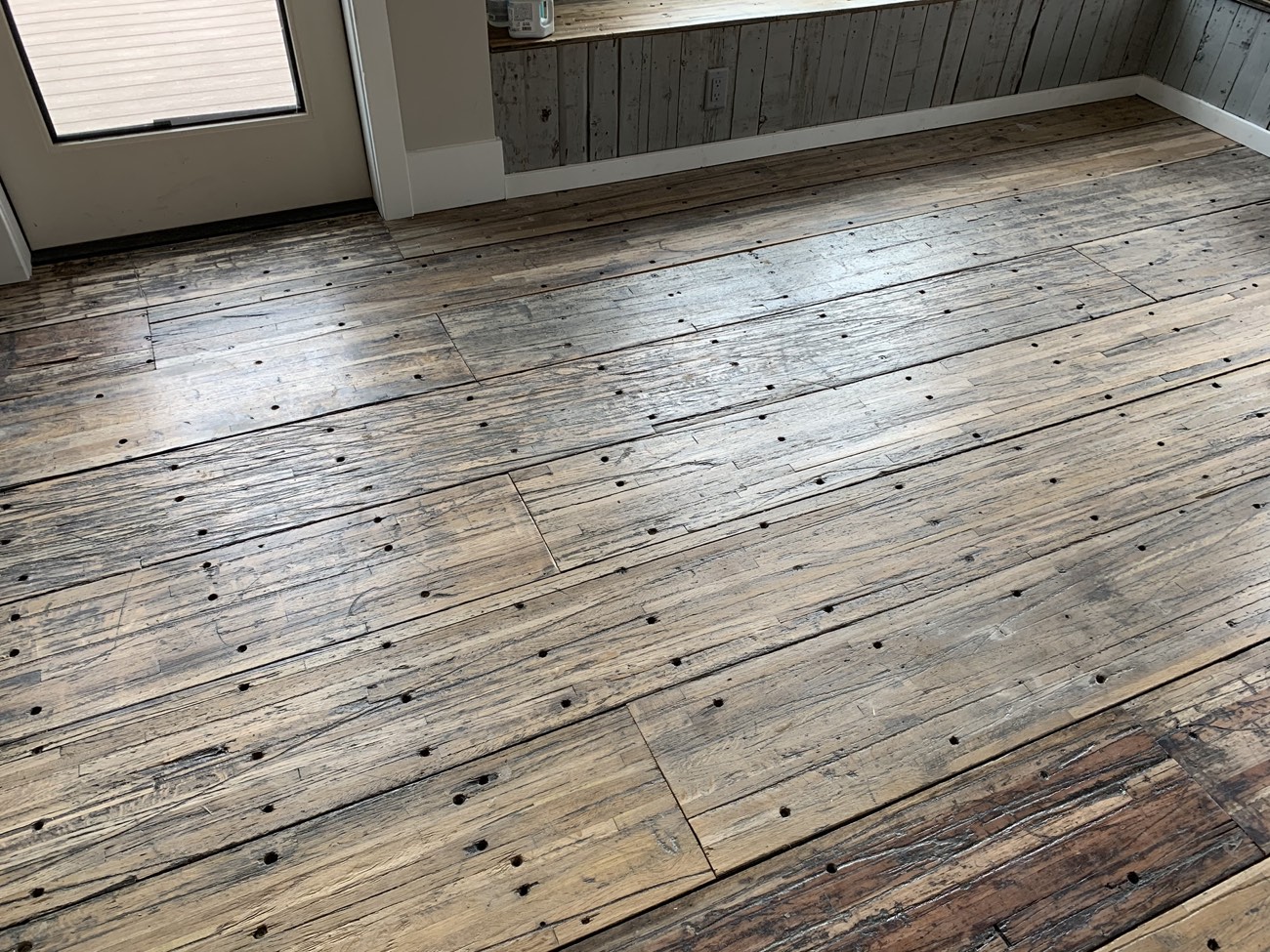 Reclaimed hardwood plank flooring installed in a room.