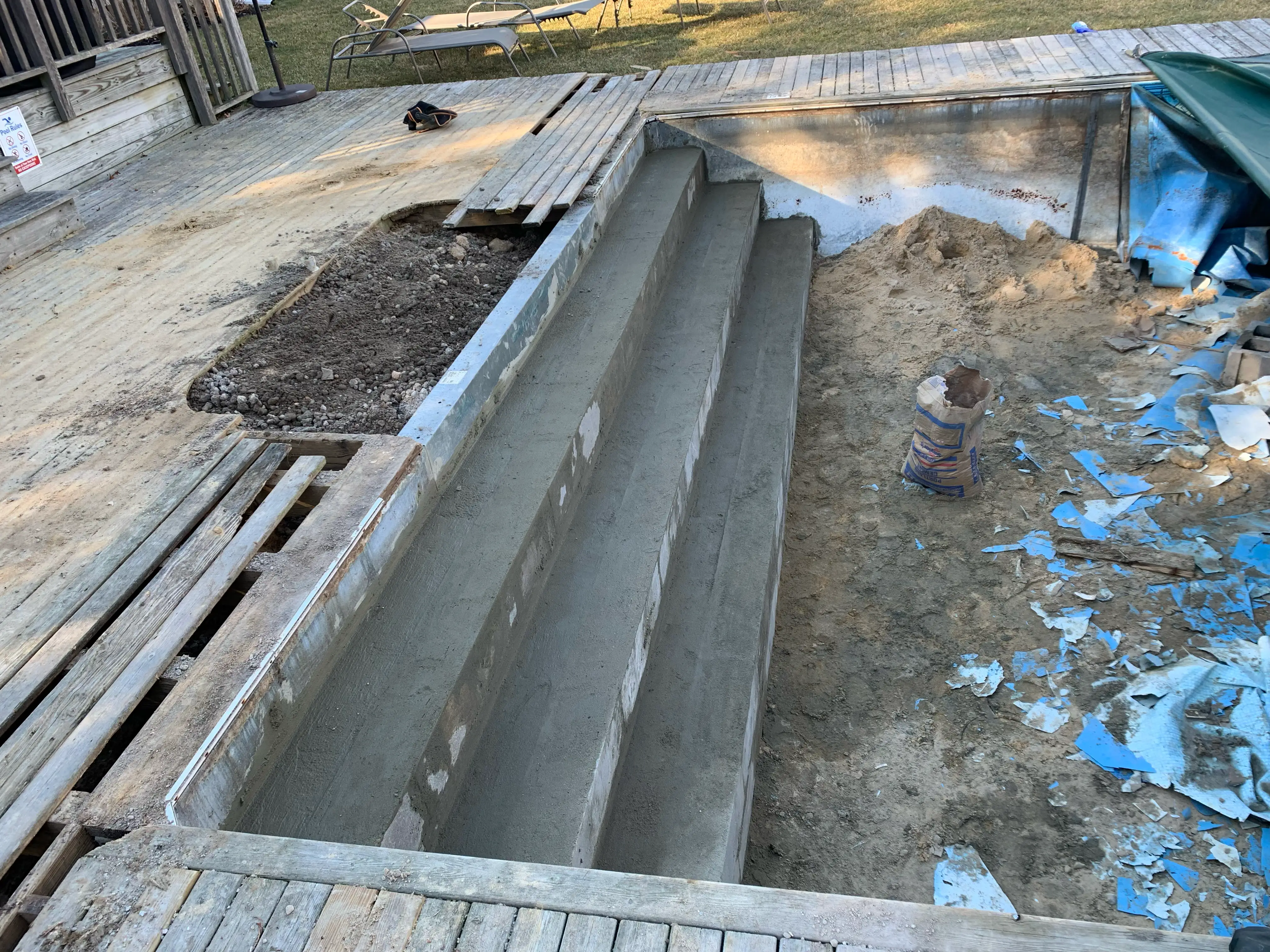 In-ground swimming pool undergoing renovation with new concrete steps.