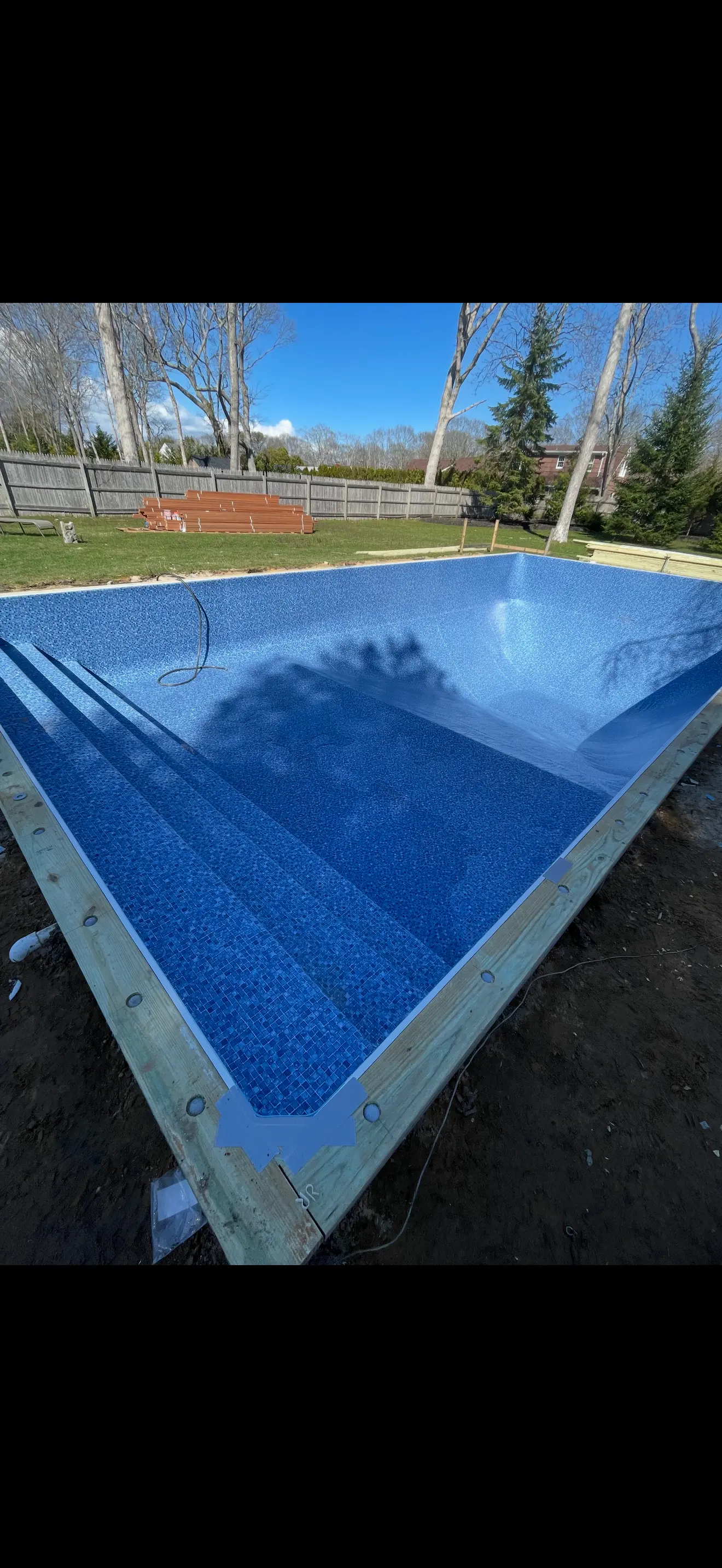 In-ground swimming pool renovation with new blue tile and built-in entry steps.