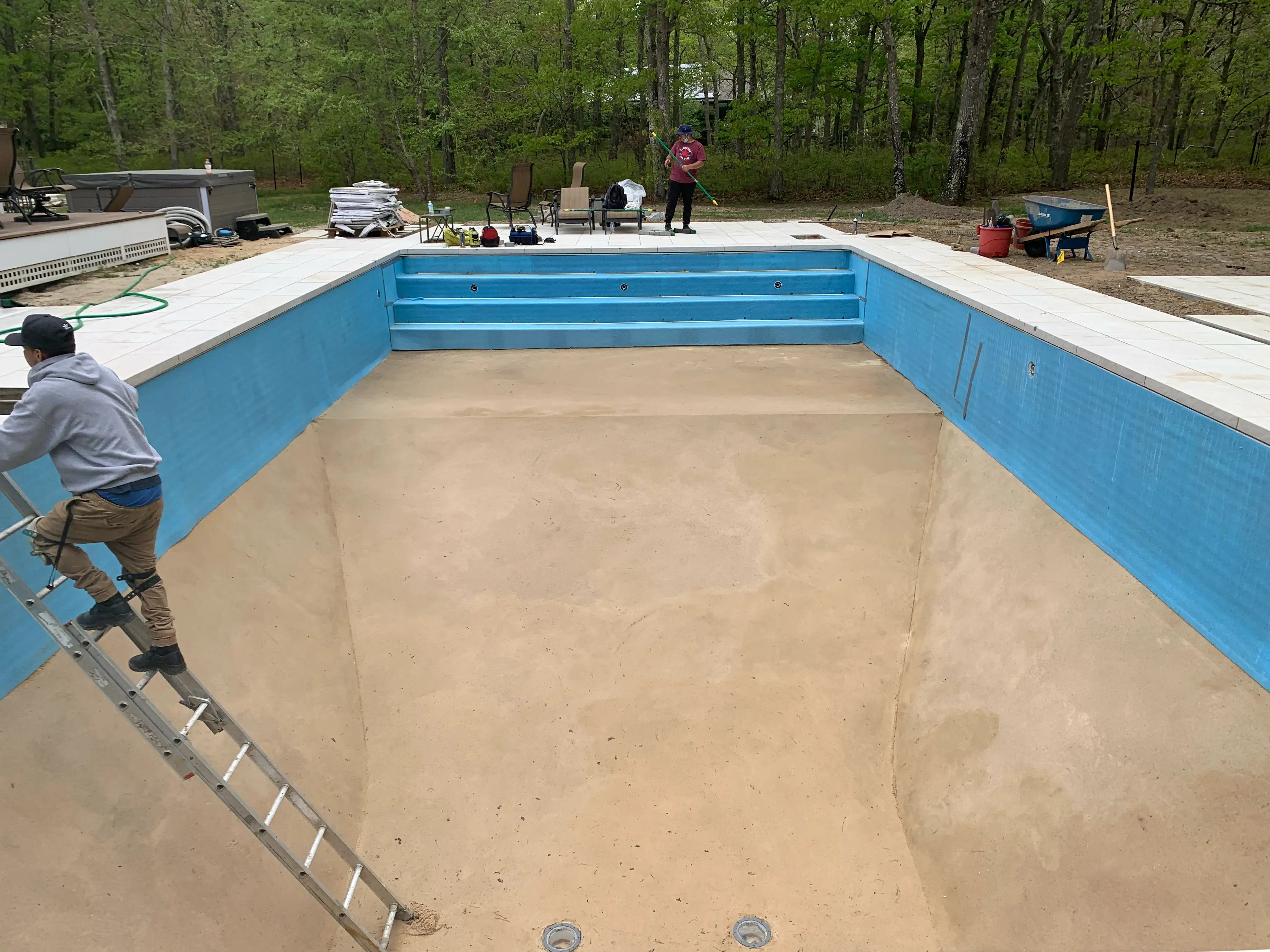 Pool renovation in progress with resurfacing work and new coping around an in-ground pool on Long Island, NY.