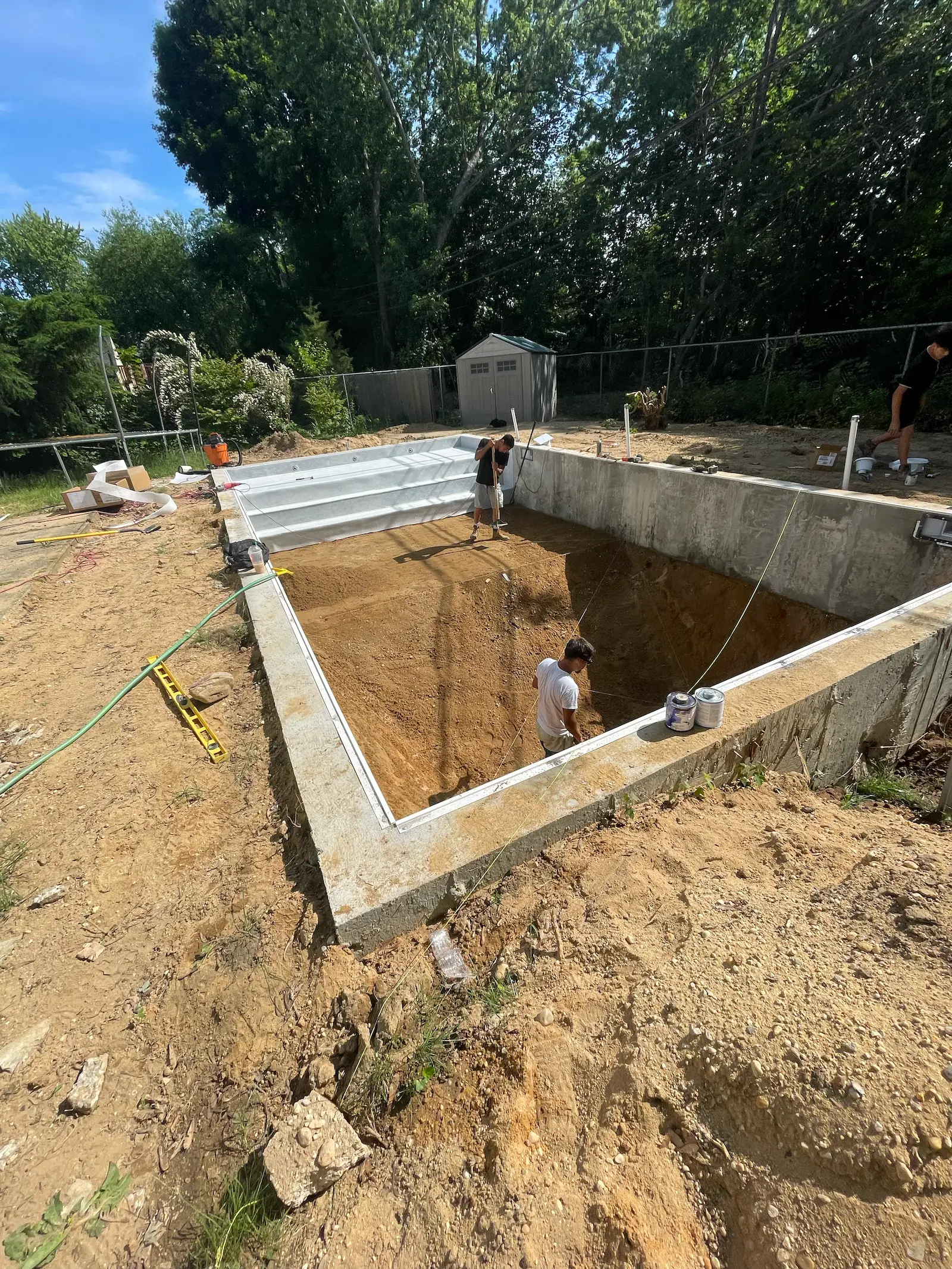 Workers installing an in-ground swimming pool during construction.