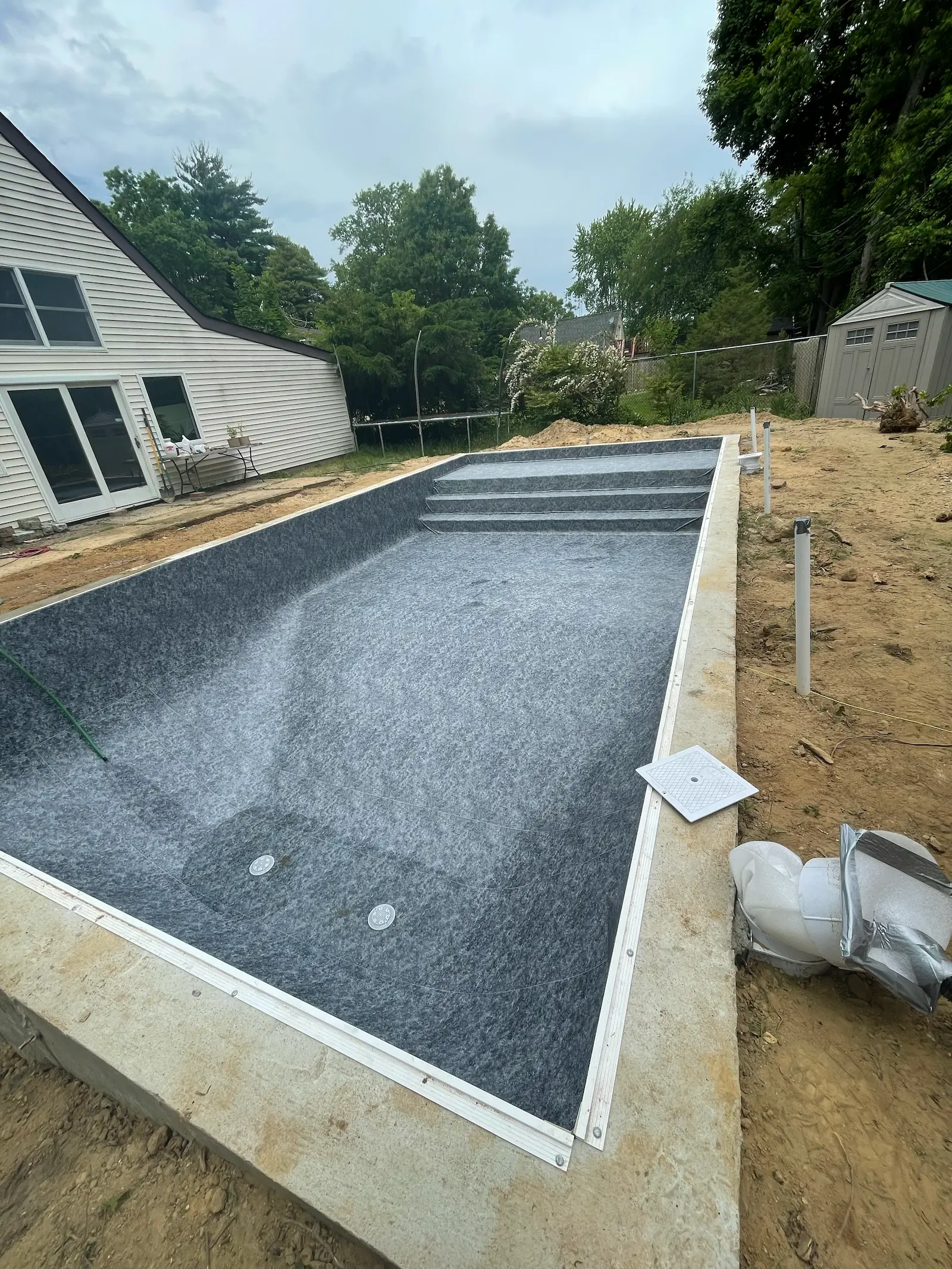 Pool renovation in progress with new gray liner, built-in steps, and surrounding deck preparation in the Hamptons near Quogue. 
