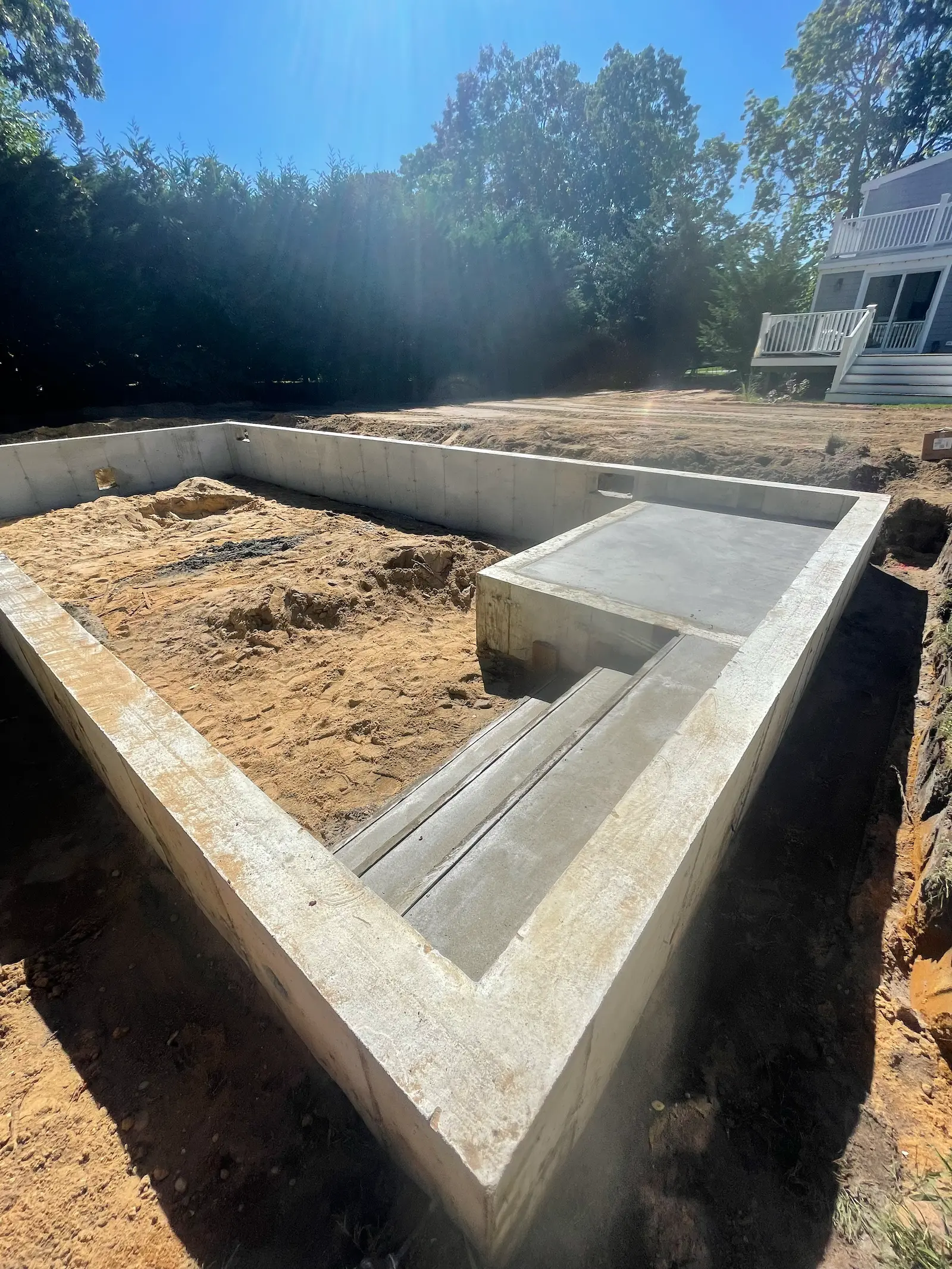 New in-ground swimming pool under construction with concrete steps and sun ledge.