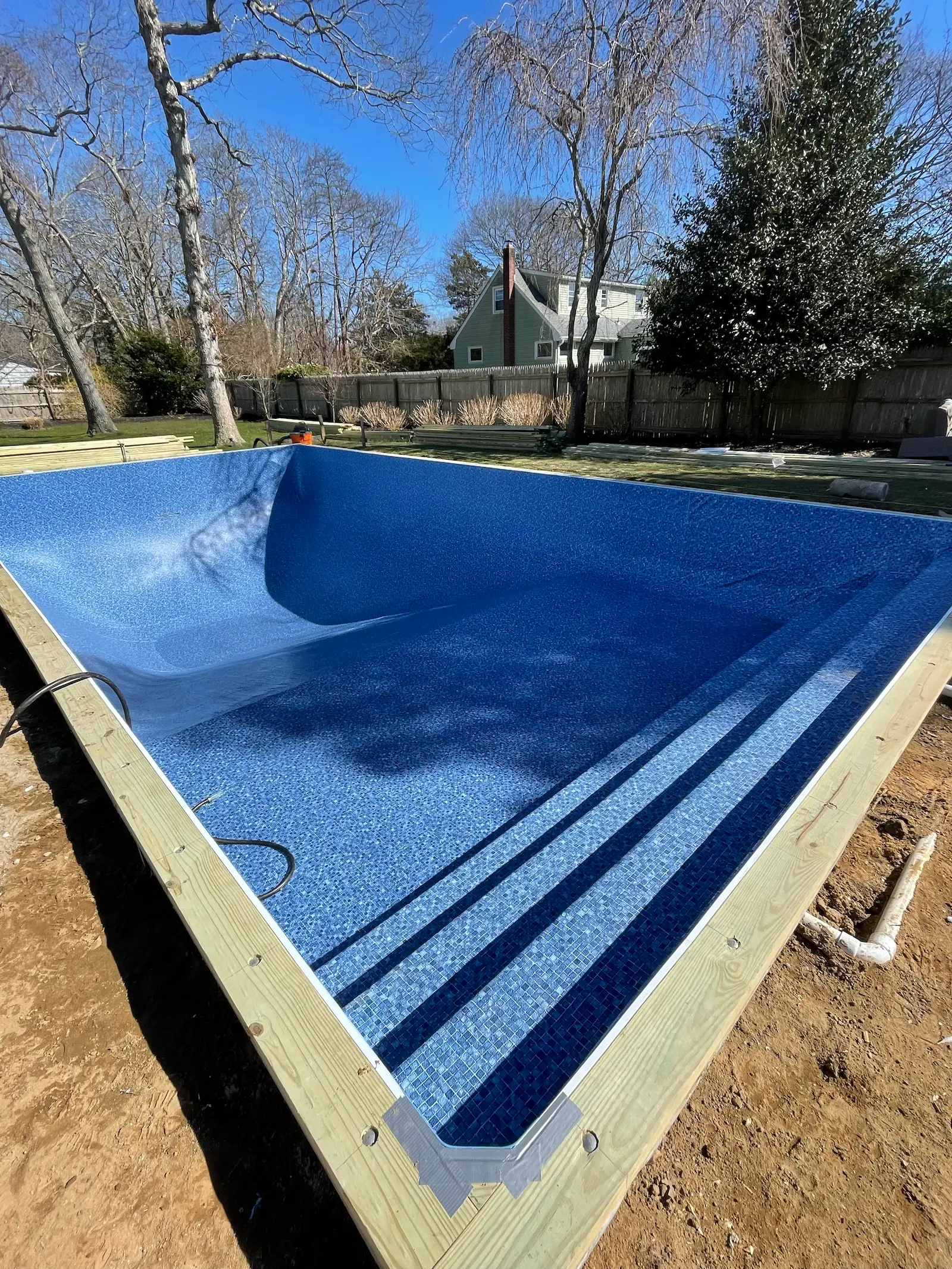 Blue-lined in-ground pool with wide entry steps nearing completion in the Hamptons.