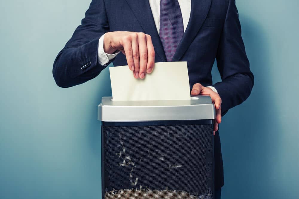 Man in suit shredding a document in a paper shredder