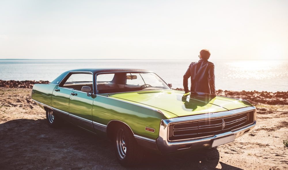 Man standing proudly next to a classic car