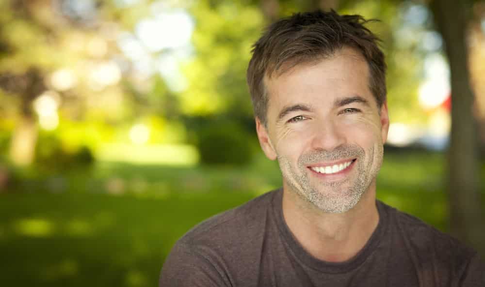 Smiling man outdoors with blurred green background