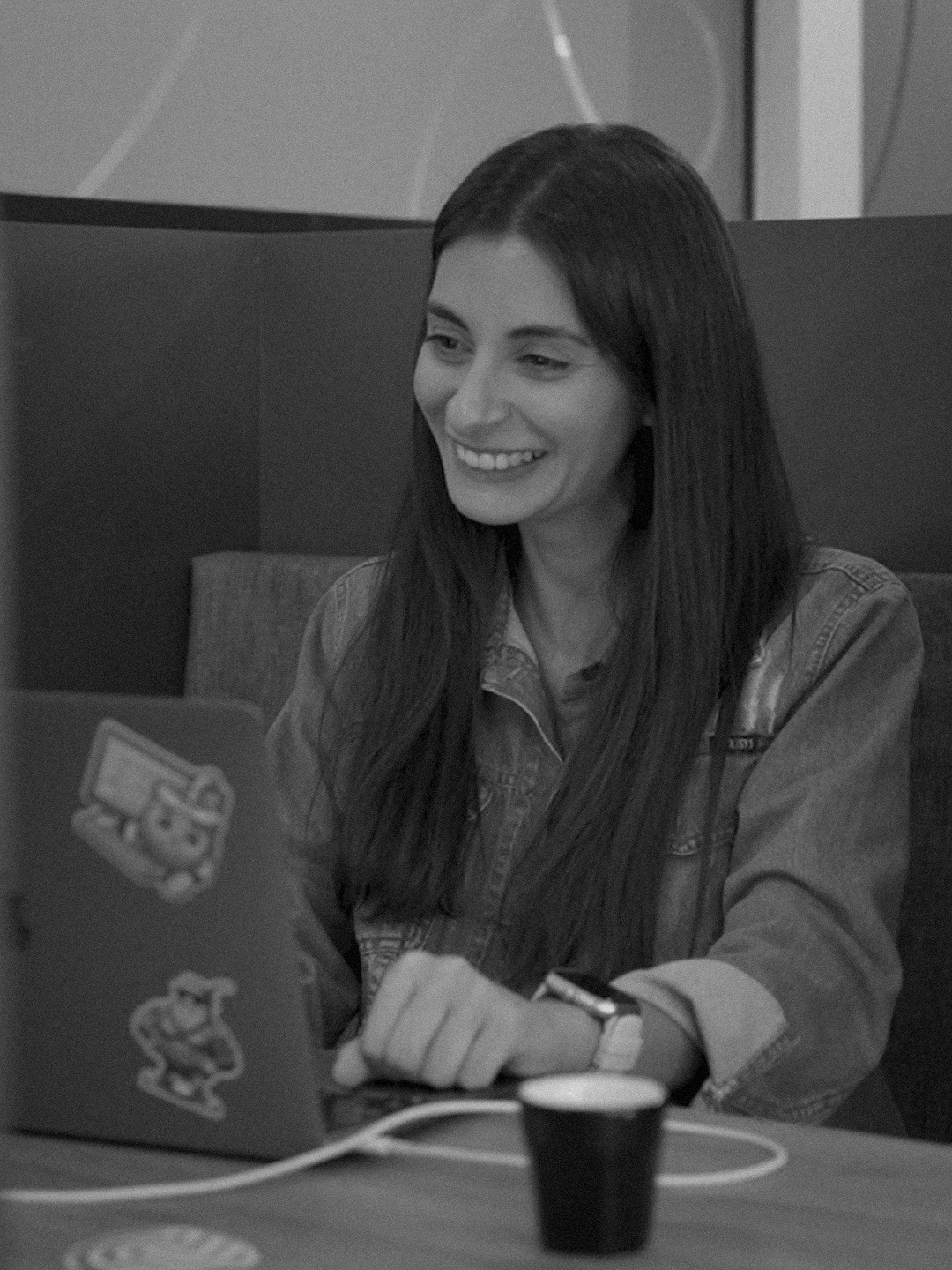 Tall frame: an engineer at her laptop, mid-conversation, smiling