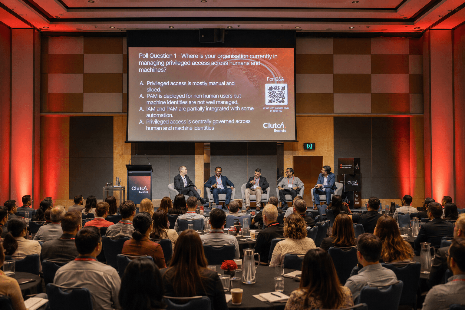 A panel of security leaders on stage in front of a full room, with an AI security poll on the screen