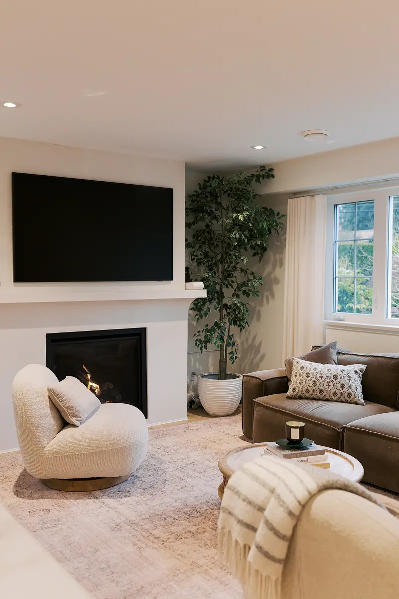 Living room with a fireplace, wall-mounted TV and a cream swivel chair, Pemberton Heights renovation