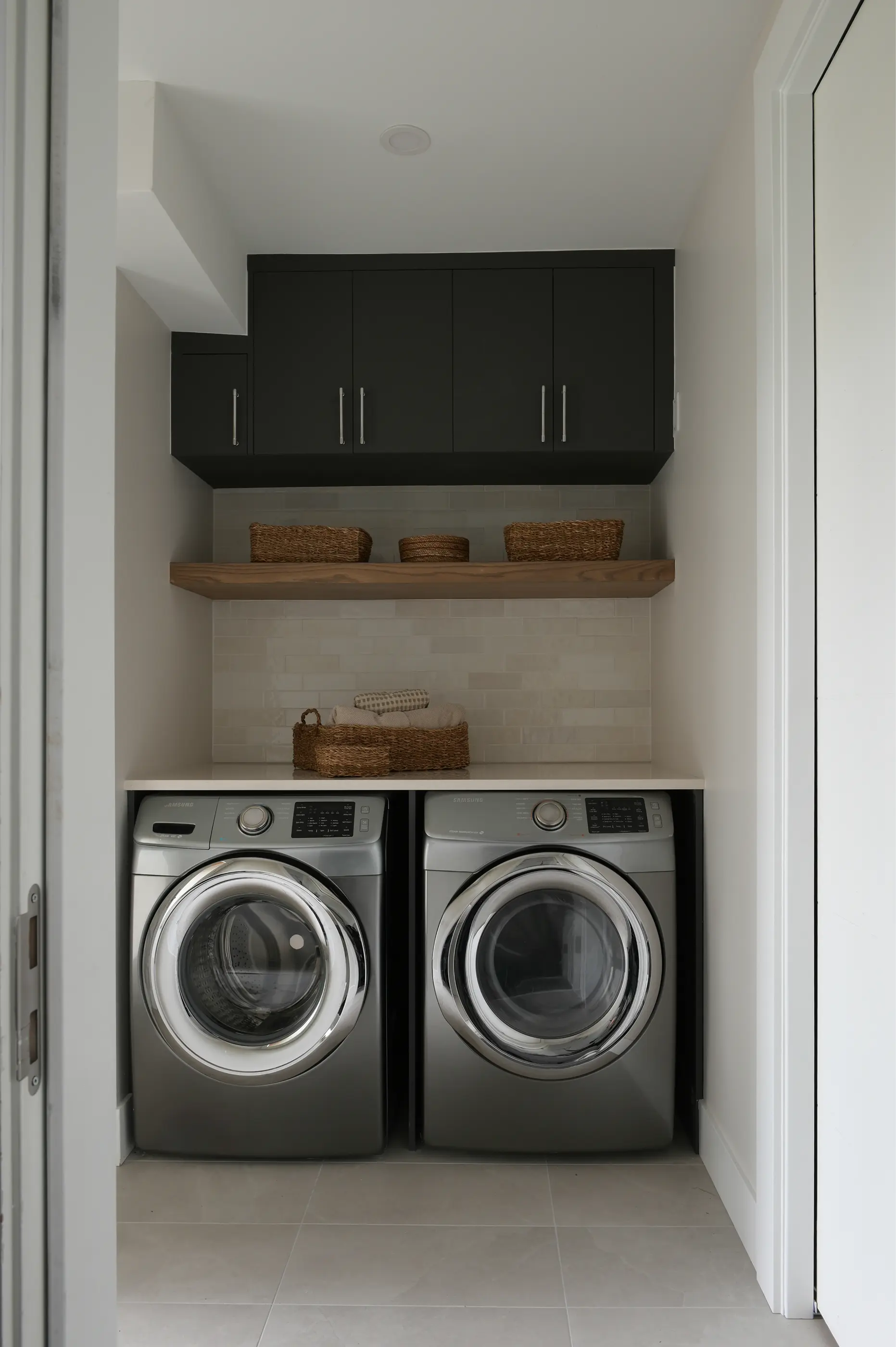 Laundry nook with dark cabinets, a floating wood shelf and side-by-side washer and dryer, Baird Avenue renovation