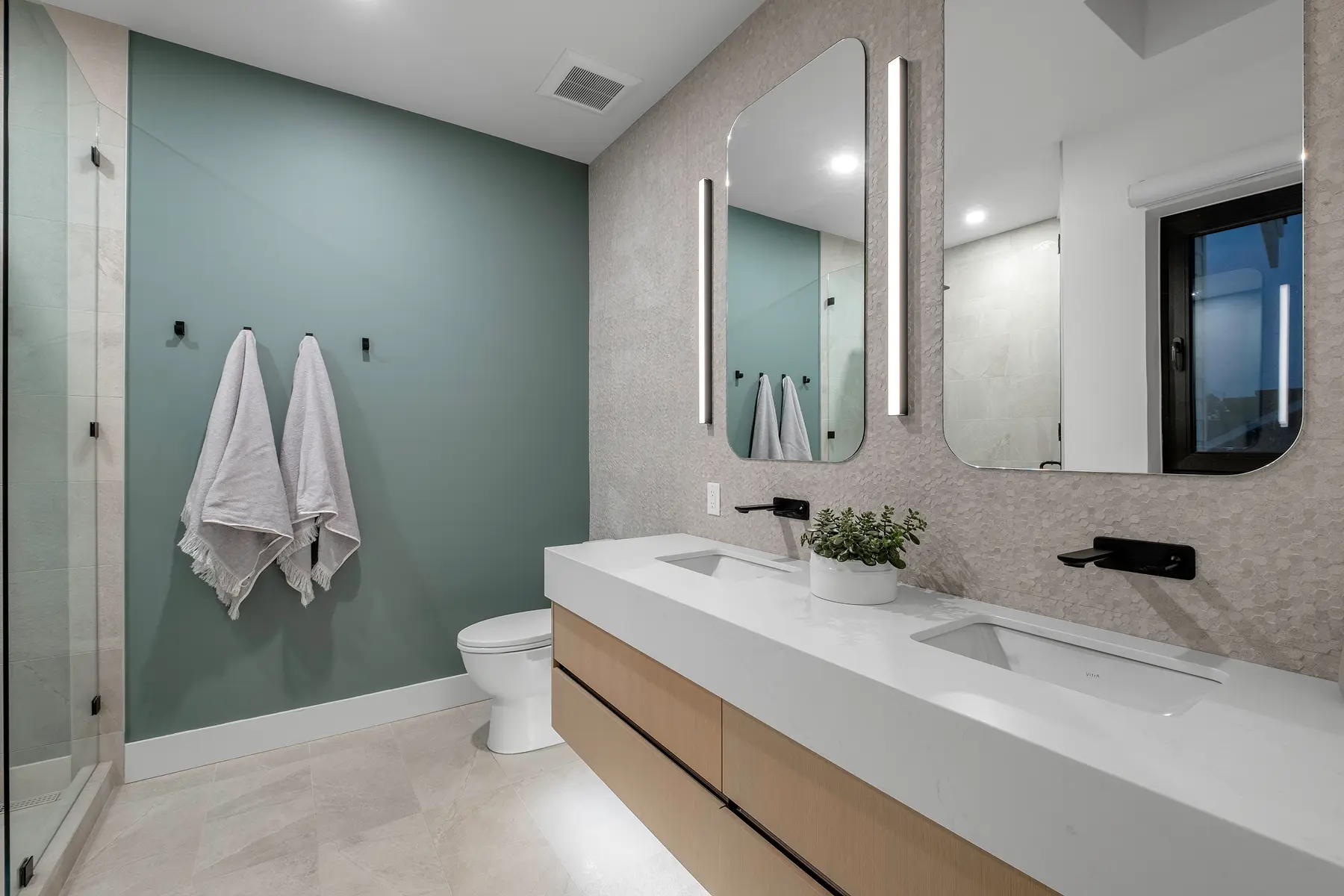 Bathroom with a green feature wall, double vanity and lit mirrors, 4th Street duplex