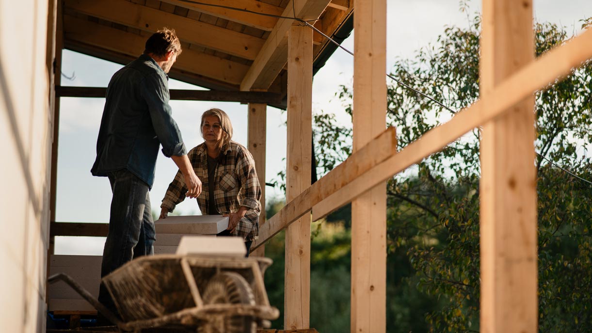 Two people working on a new house build in a rural setting