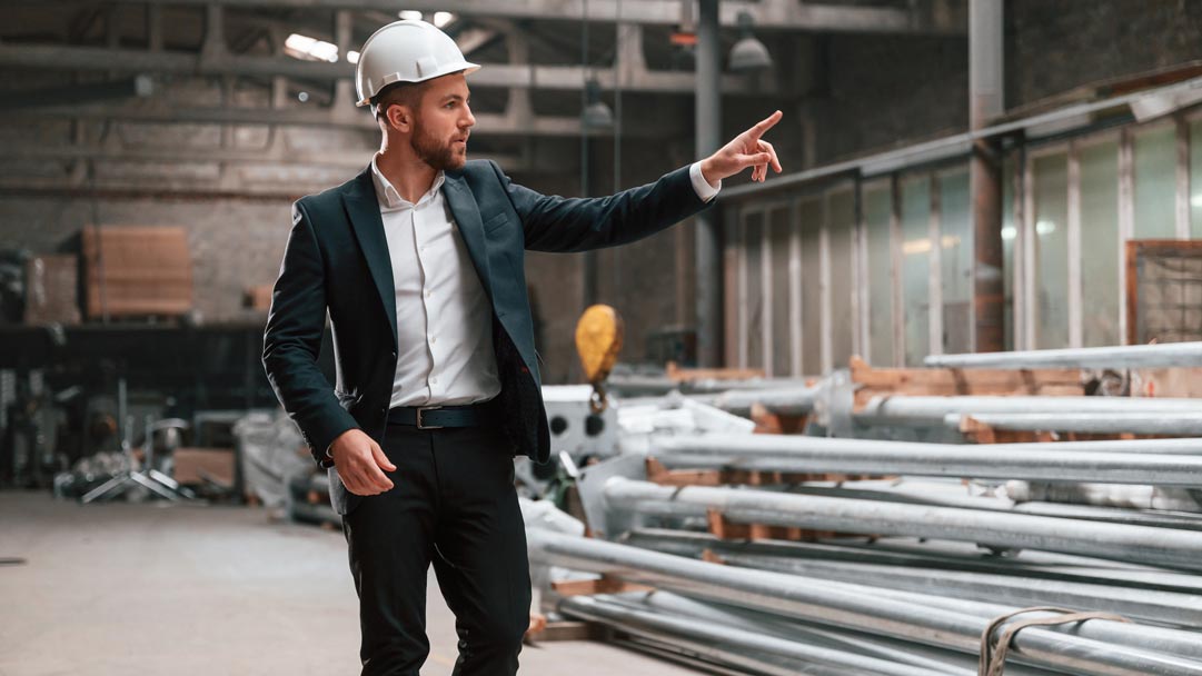 Man wearing a hard hat pointing something out in an industrial setting