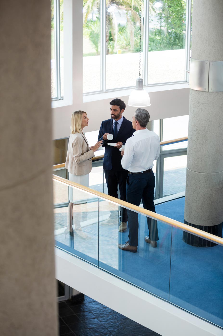 Business professionals chatting together while holding coffee cups